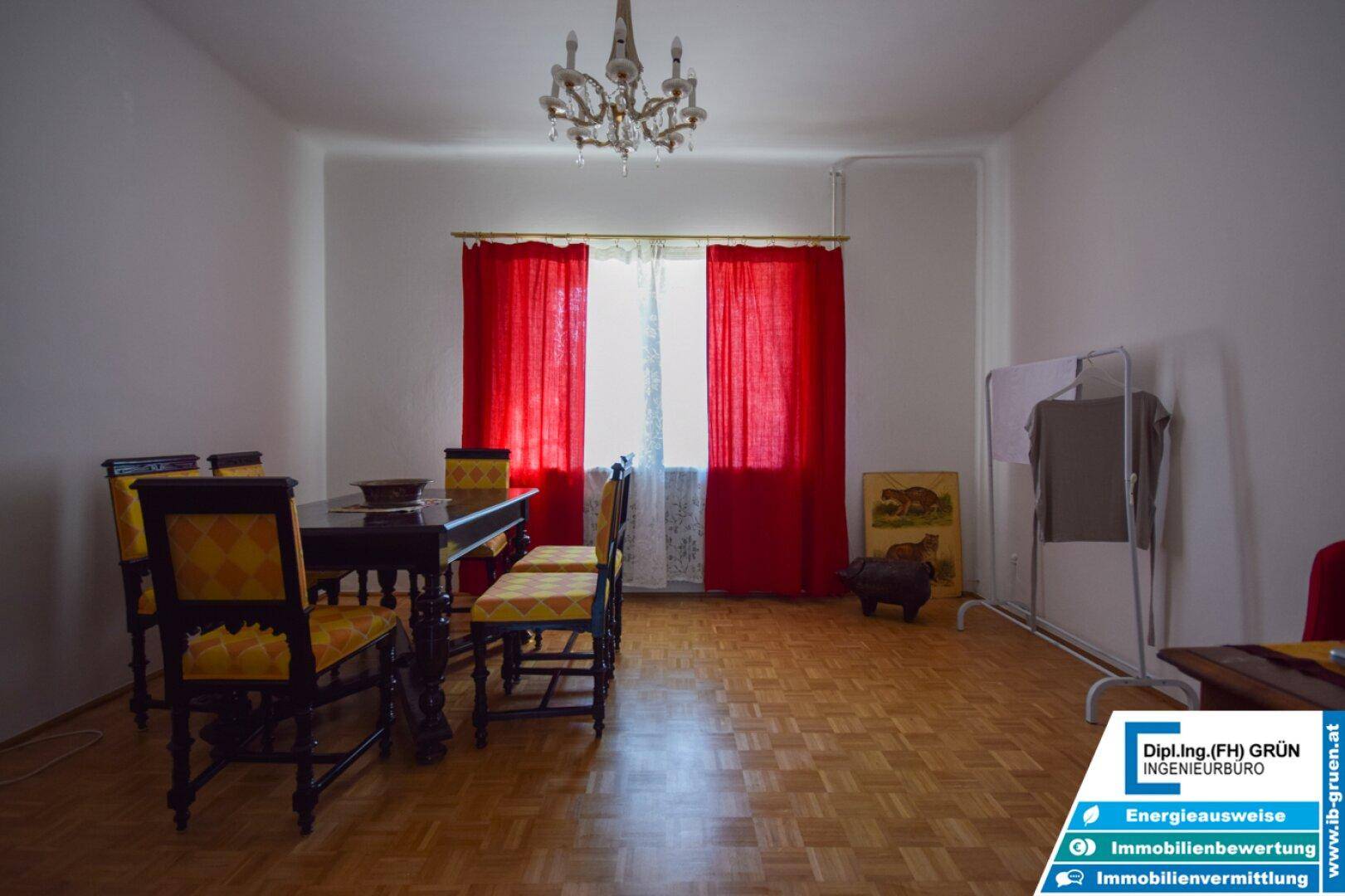 Esszimmer mit Parkettboden, rotem Vorhang und einem klassischen Esstisch mit Stühlen.