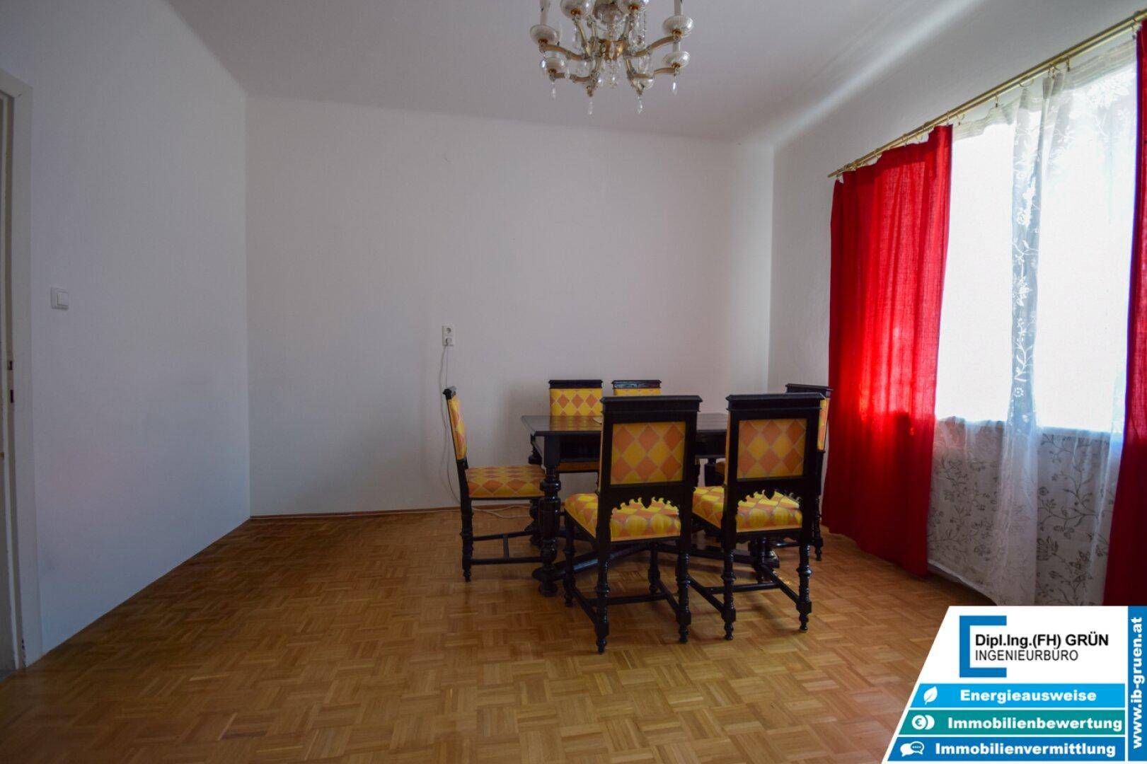 Esszimmer mit Parkettboden, rotem Vorhang und einem klassischen Esstisch für mehrere Personen.