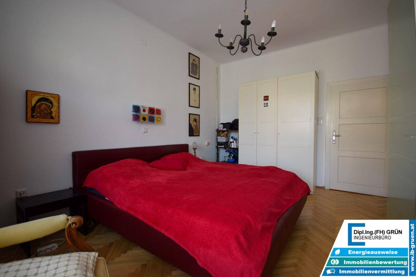 Schlafzimmer mit Doppelbett, Parkettboden, weißem Kleiderschrank und einer Tür.