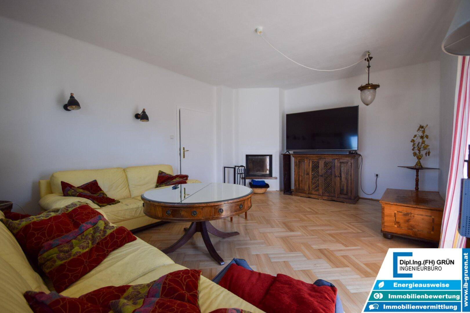 Gemütliches Wohnzimmer mit Parkettboden, gelben Sofas und einem Fernseher.