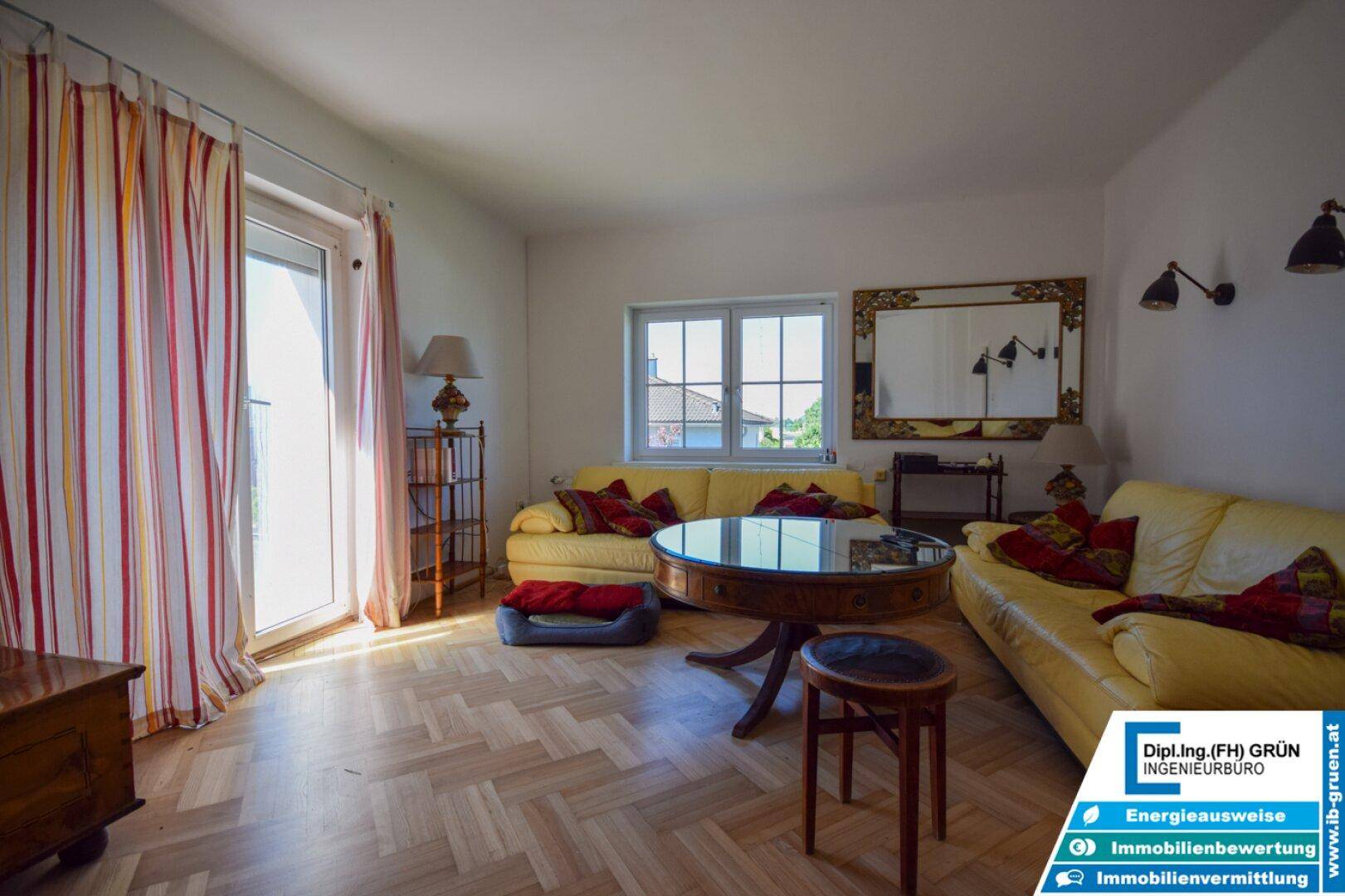 Helles Wohnzimmer mit Parkettboden, Zugang zum Balkon und einem großen Spiegel.