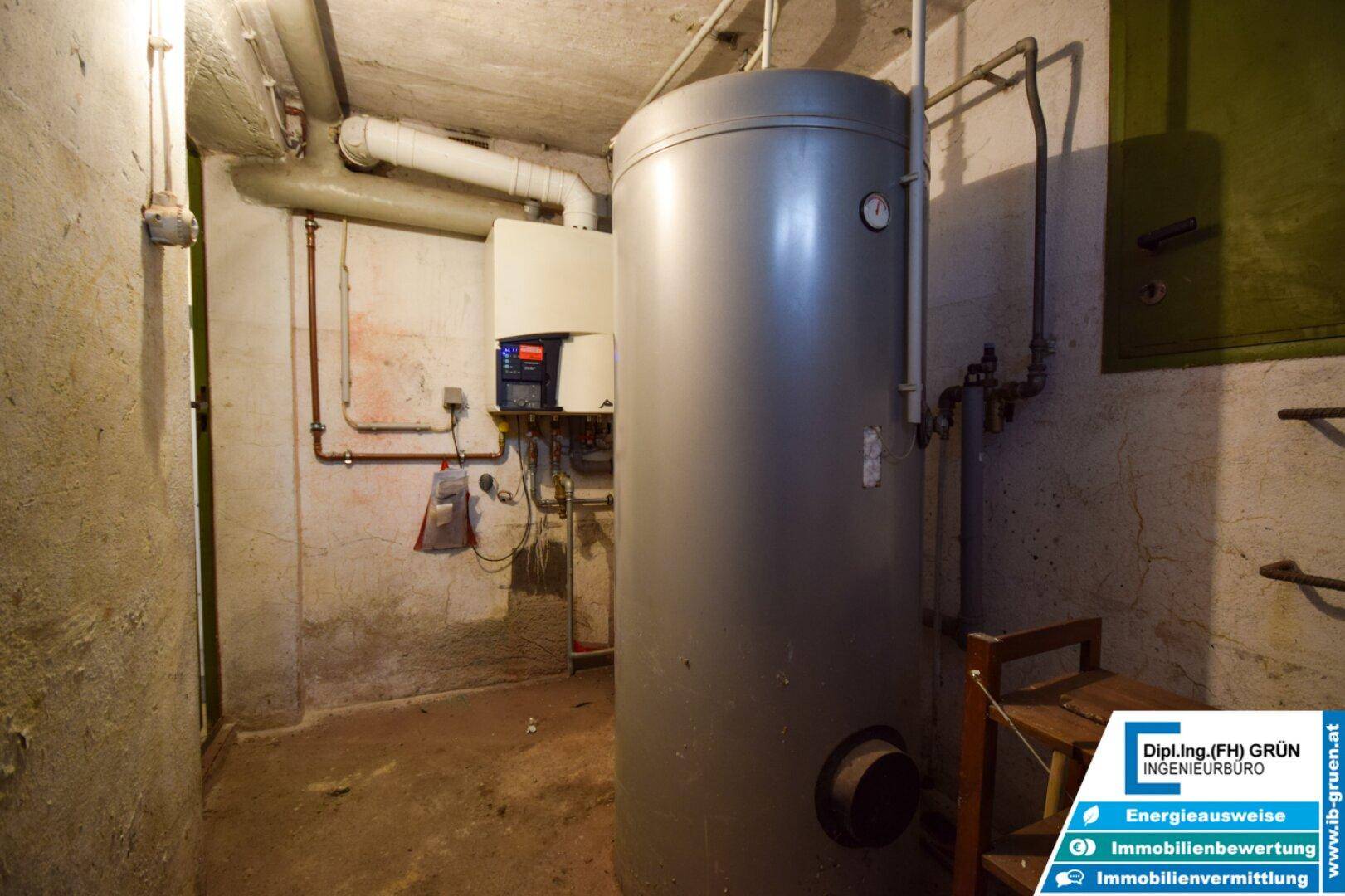 Heizungsraum mit Warmwasserspeicher und Heizkessel im Kellerbereich.