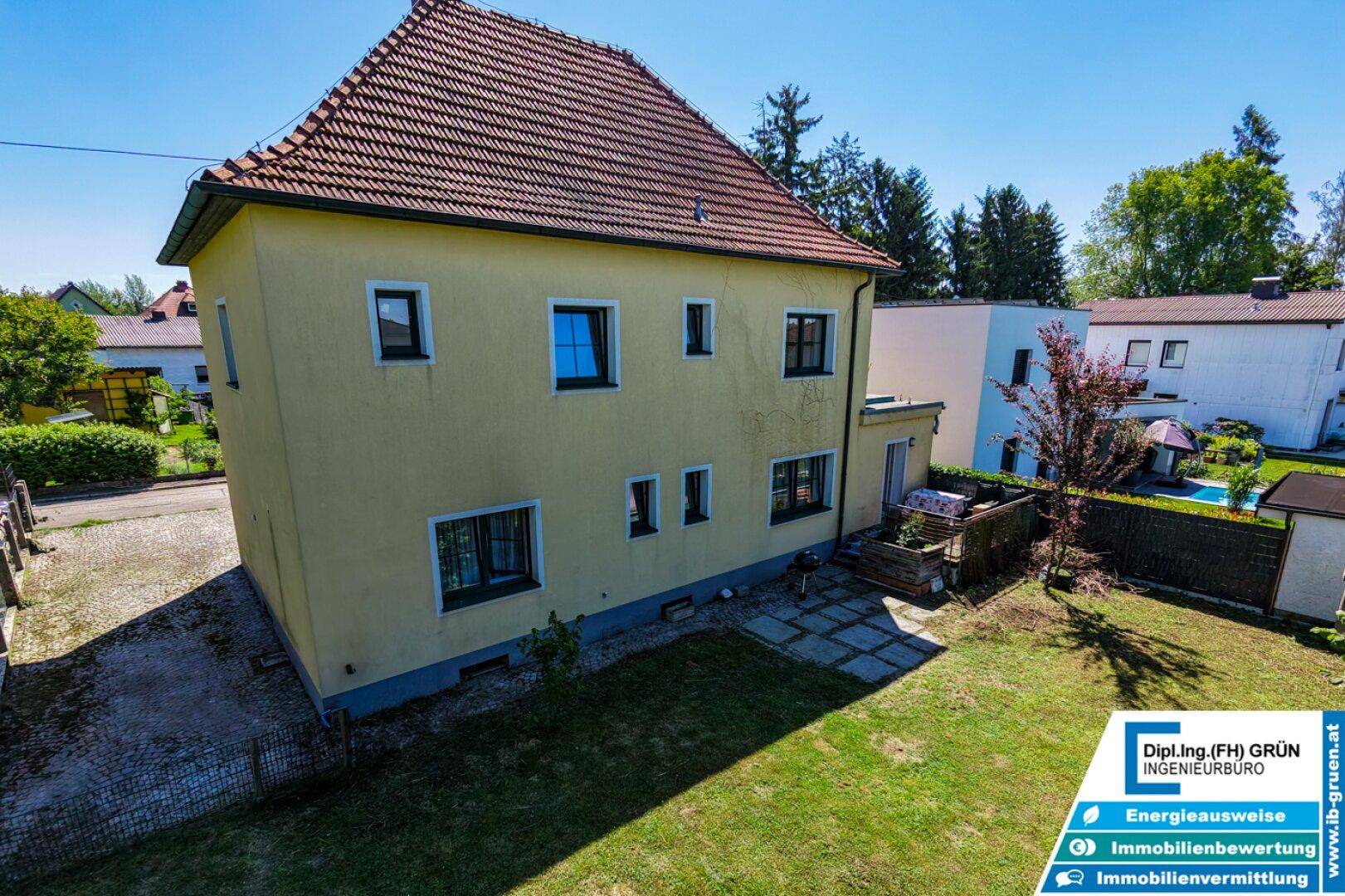 Seitenansicht des Hauses mit Garten, Rasenfläche und angrenzender Terrasse.