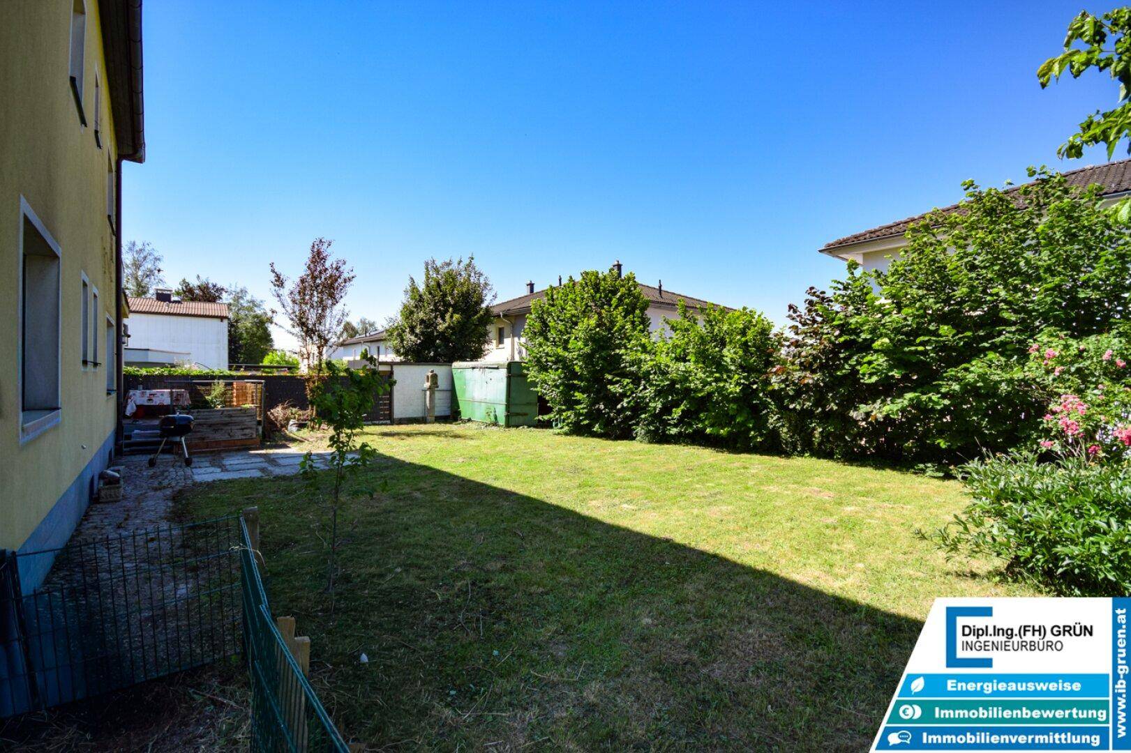 Großer, gepflegter Gartenbereich mit Rasen, Büschen und einem Grillplatz.