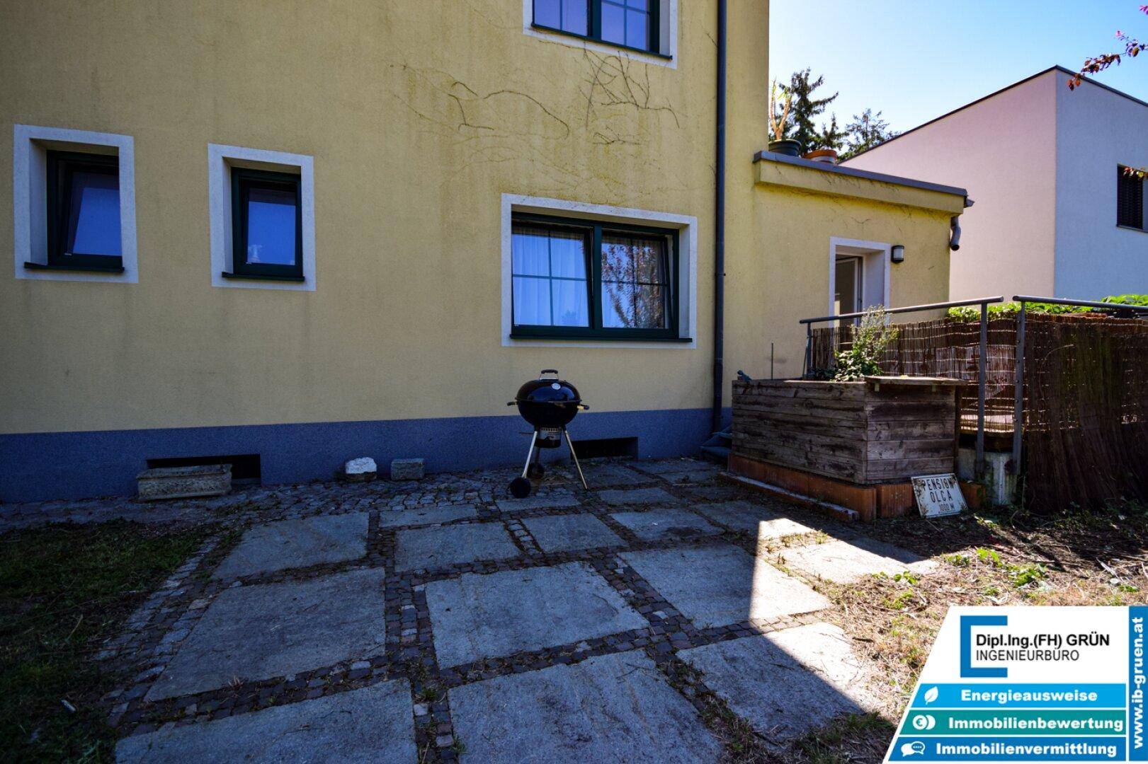 Gepflasterte Terrasse mit Grillbereich direkt am Haus, ideal für sommerliche Abende.