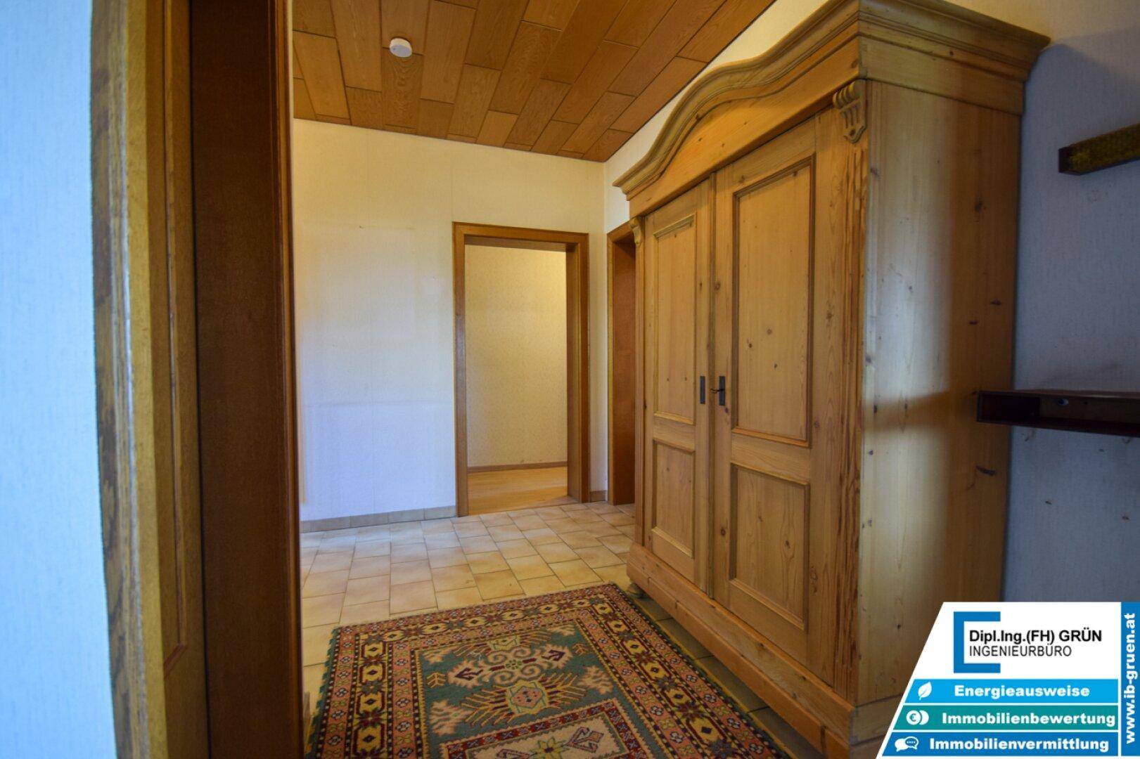 Flur mit rustikalem Holzschrank, Fliesenboden und Holzdecke, führt zu weiteren Räumen.