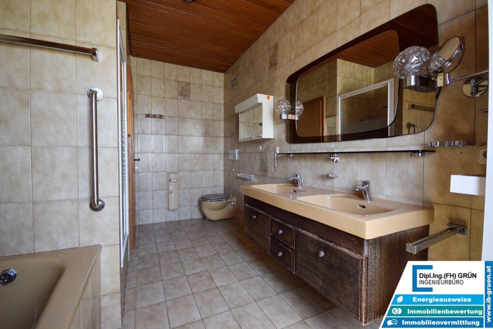 Badezimmer mit Badewanne, Doppelwaschbecken und Fliesenboden, bietet ausreichend Platz.