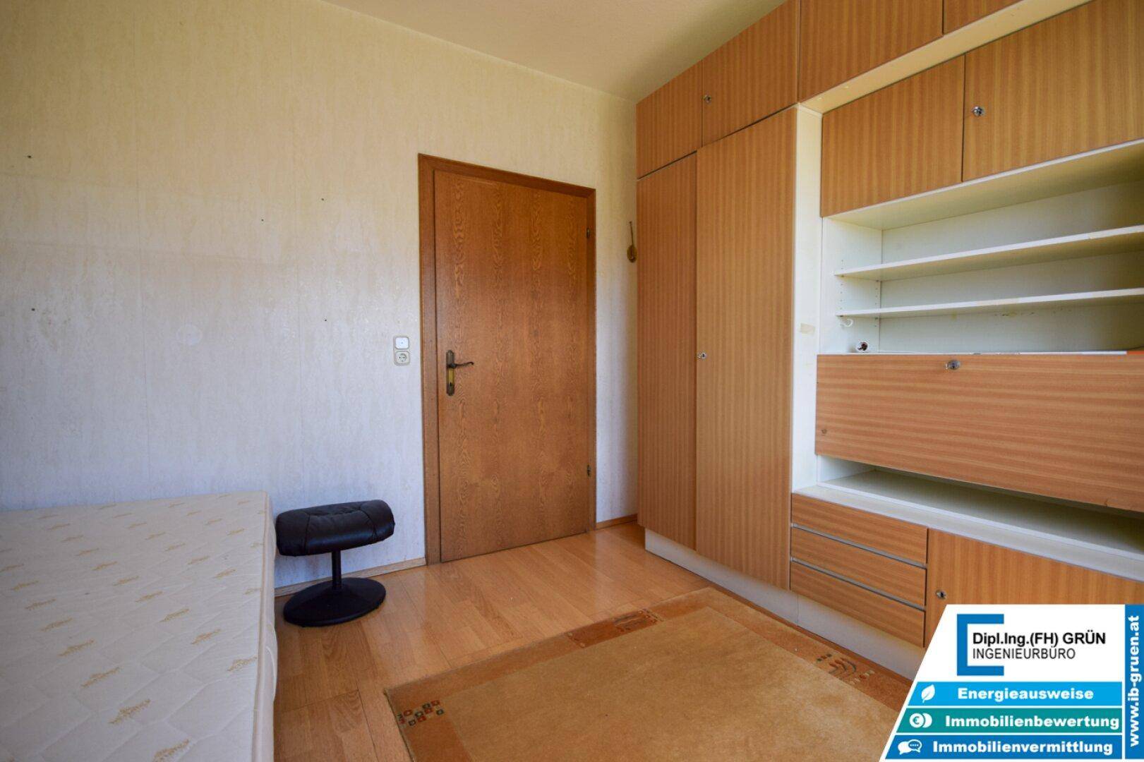 Schlafzimmer mit Einbauschränken, Einzelbett und Holzfußboden, bietet viel Stauraum.