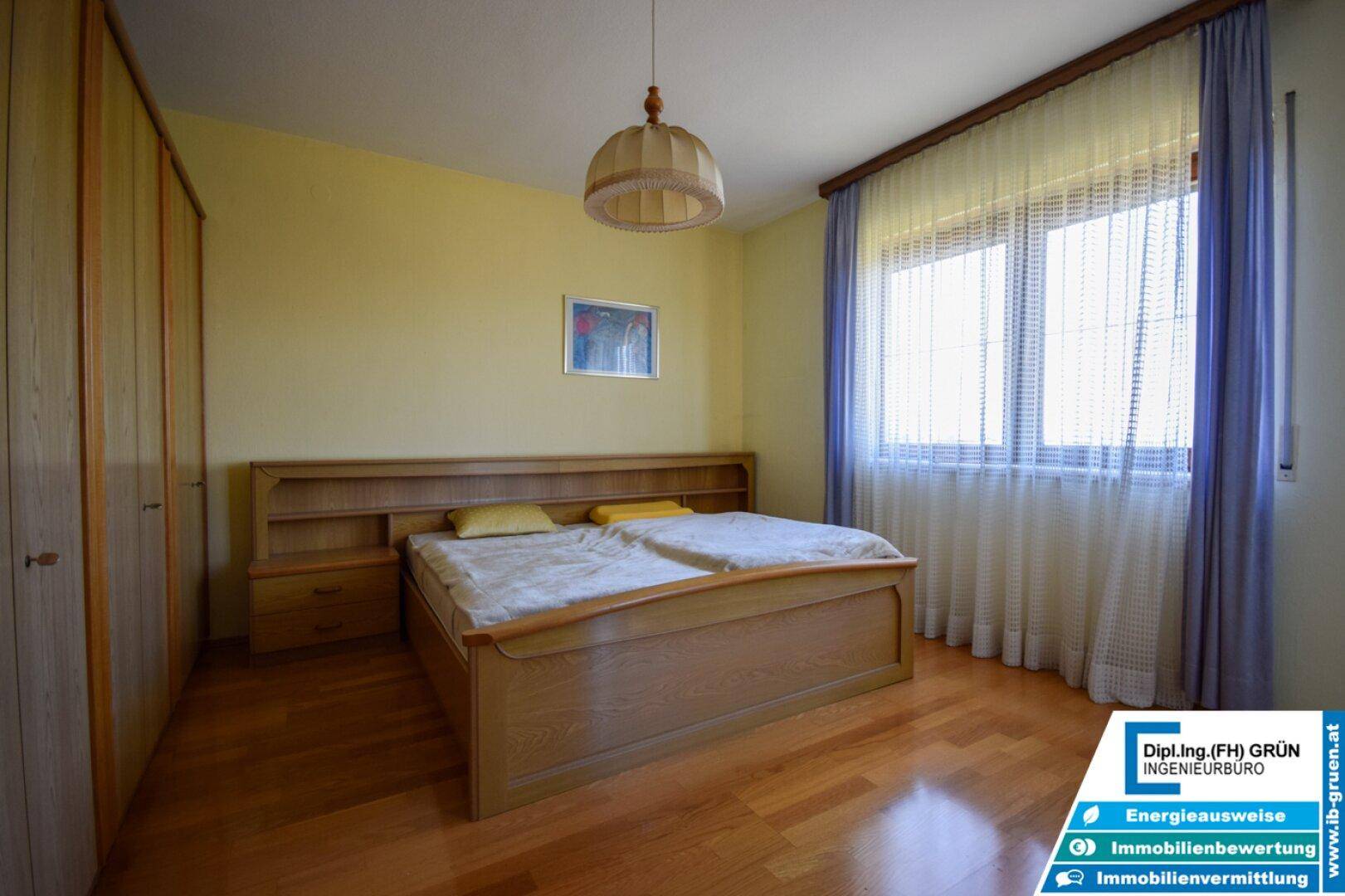 Geräumiges Schlafzimmer mit Doppelbett, Holzfußboden und großen Fenstern.