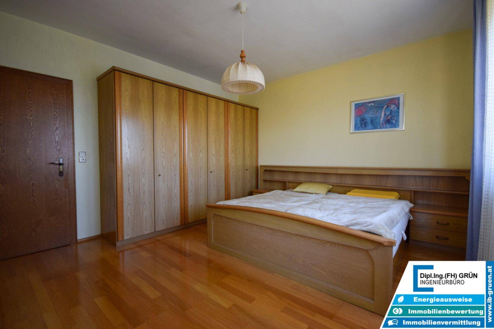 Schlafzimmer mit Doppelbett, großen Einbauschränken und Holzfußboden.
