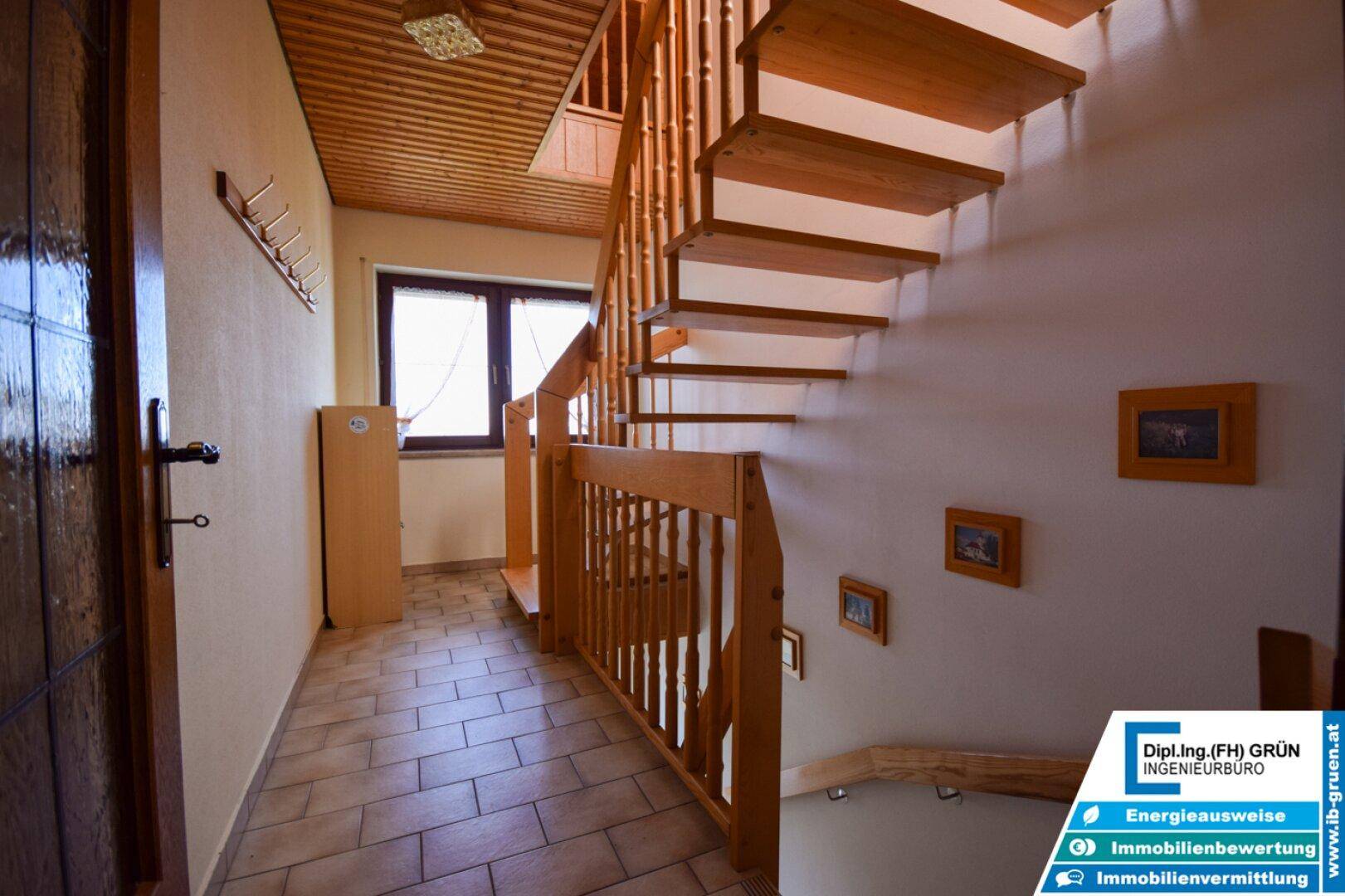 Treppenhaus mit Holztreppe und Fliesenboden, führt in die oberen Etagen.