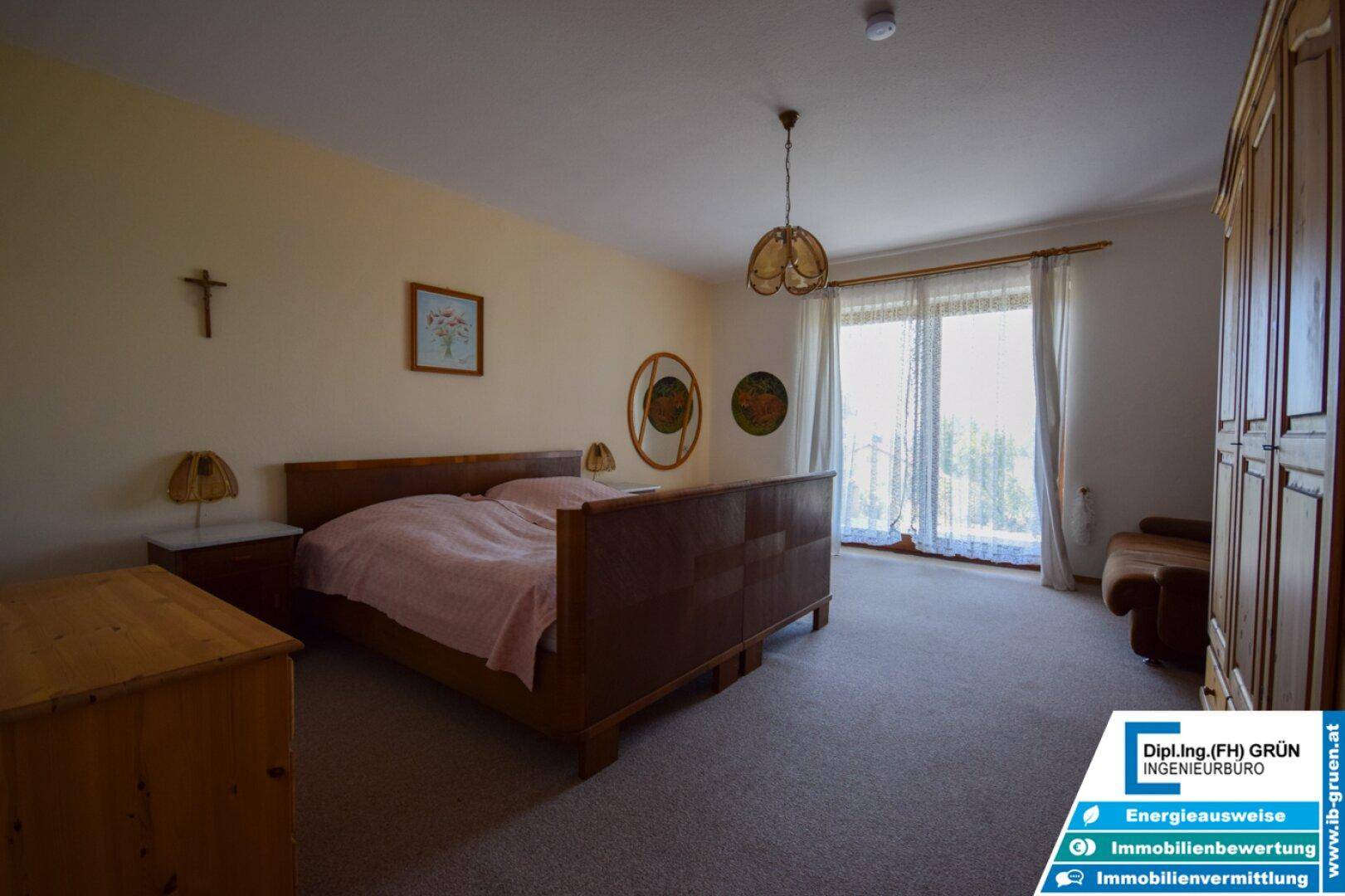Schlafzimmer mit Doppelbett, Teppichboden und Zugang zu einem Balkon.