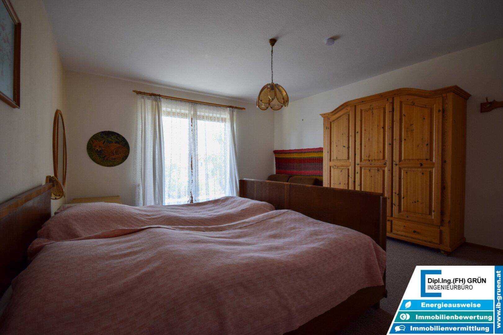 Geräumiges Schlafzimmer mit Holzschrank, Doppelbett und hellem Teppichboden.