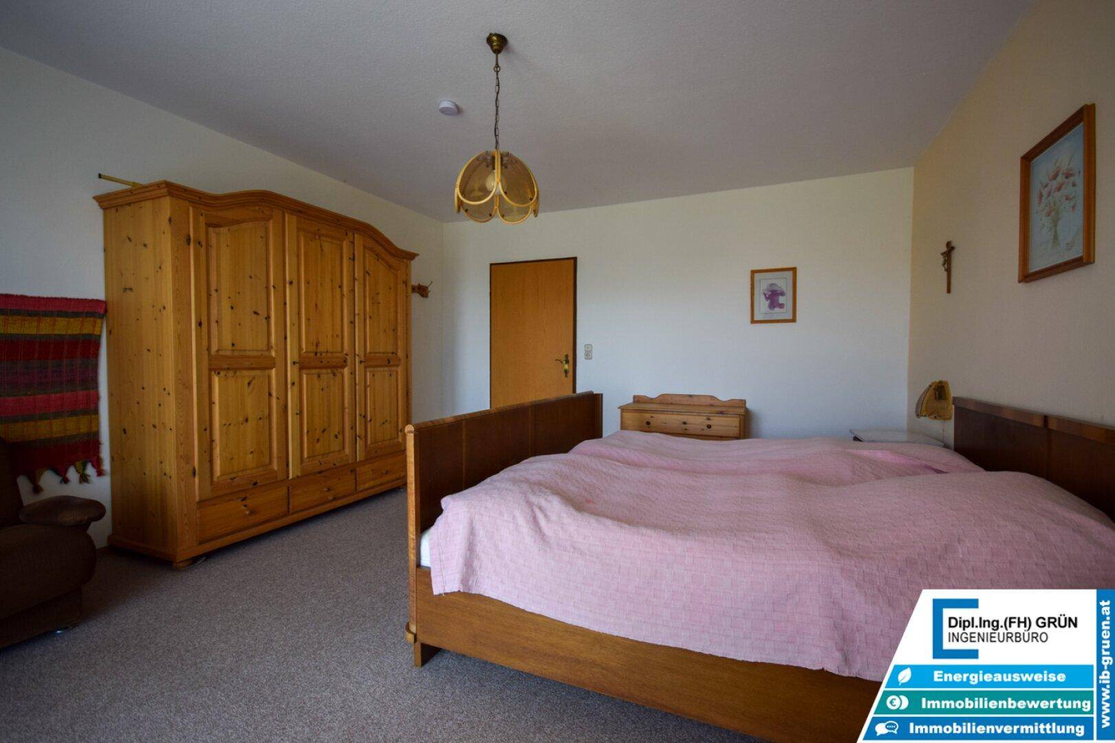 Schlafzimmer mit traditionellem Holzschrank, Doppelbett und Teppichboden.