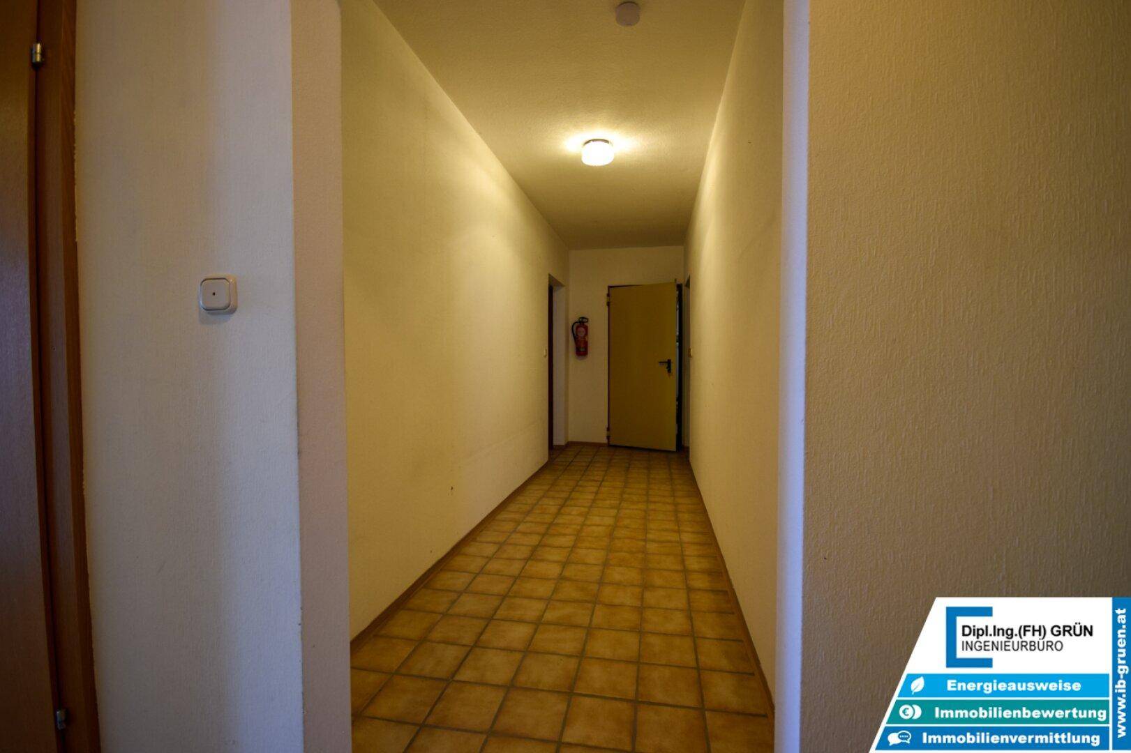 Langer Flur mit Fliesenboden und Türen zu verschiedenen Zimmern.