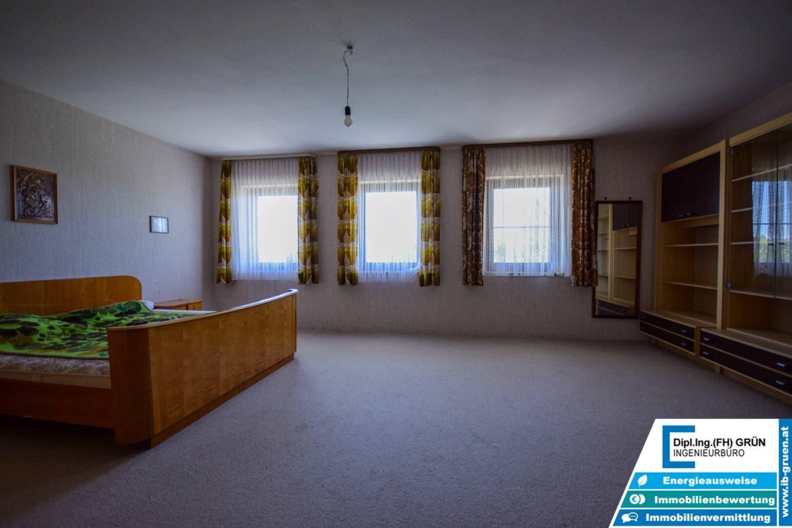 Großes Schlafzimmer mit Teppichboden, mehreren Fenstern und Einbauschränken.