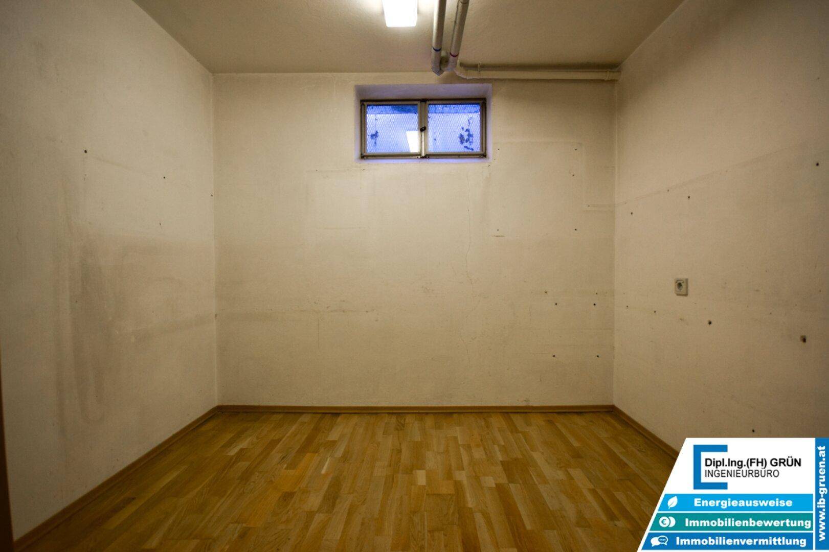 Kellerraum mit Holzparkettboden und einem kleinen Fenster für Tageslicht.