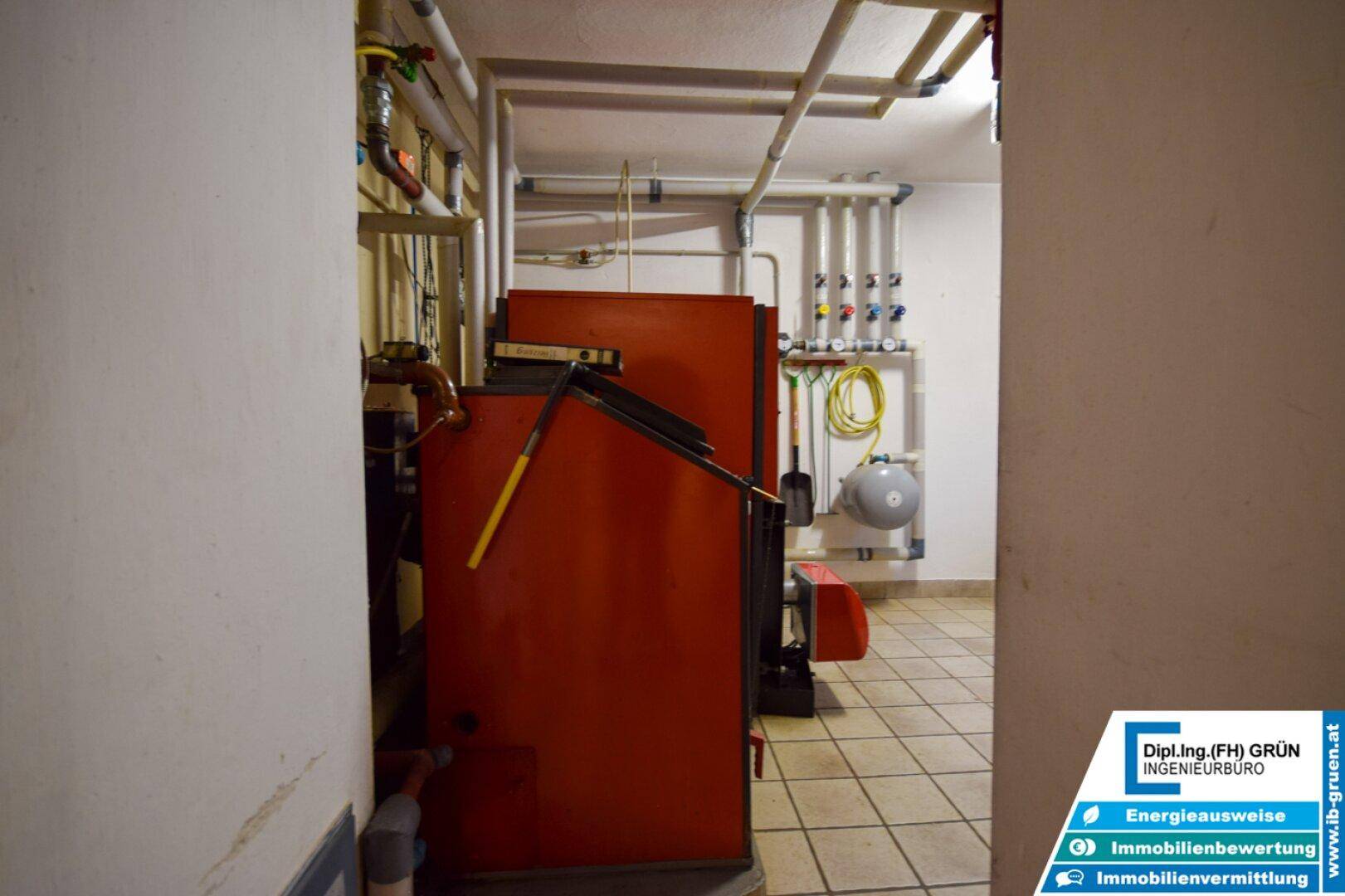 Heizungsraum mit großem Heizkessel und sichtbaren Rohrleitungen.