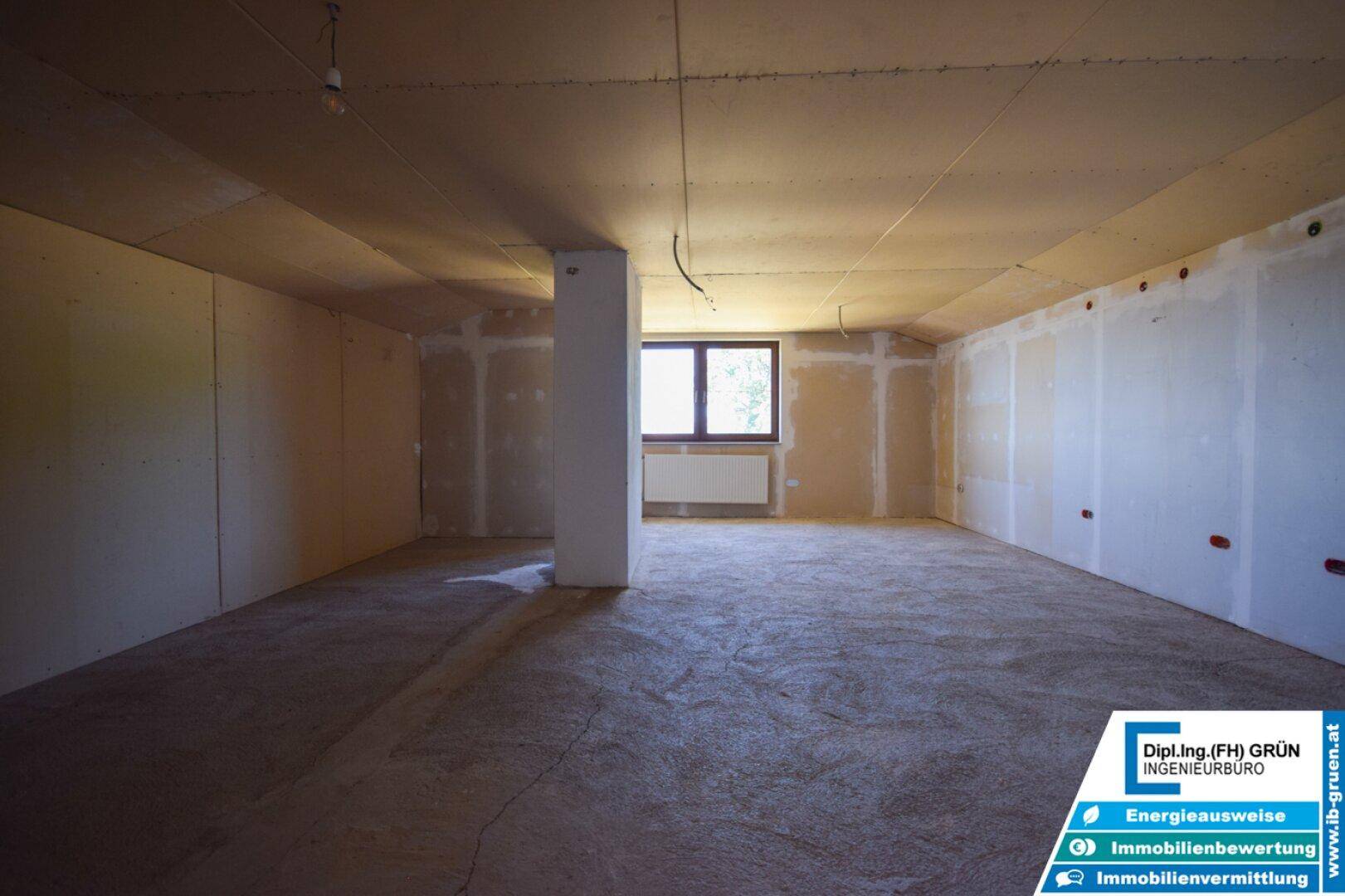 Geräumiger Innenraum im Rohbau mit Fenster und Heizkörper, bereit für den individuellen Ausbau.