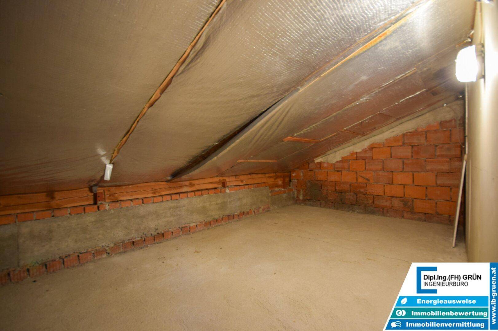 Dachbodenraum mit sichtbaren Ziegelwänden und Isolierung, bereit für den Ausbau zum Wohnraum.