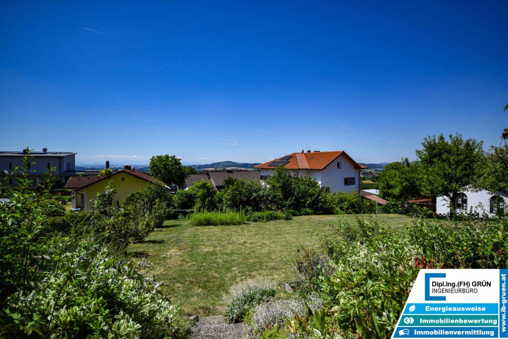 Weitläufiger Garten mit Rasenfläche und Blick auf die umliegende, grüne Landschaft.