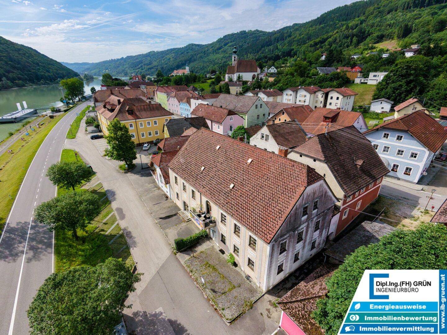 Luftaufnahme des malerischen Dorfes mit traditionellen Häusern und roten Ziegeldächern am Fluss.