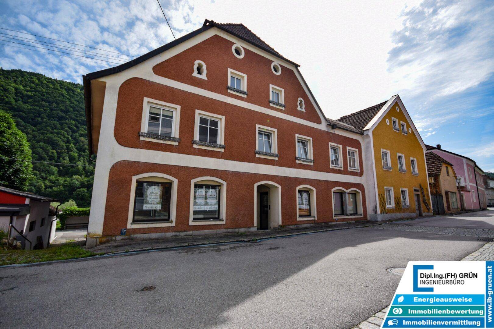 Traditionelles Gebäude mit rotbrauner Fassade und weißen Akzenten an einer Dorfstraße.