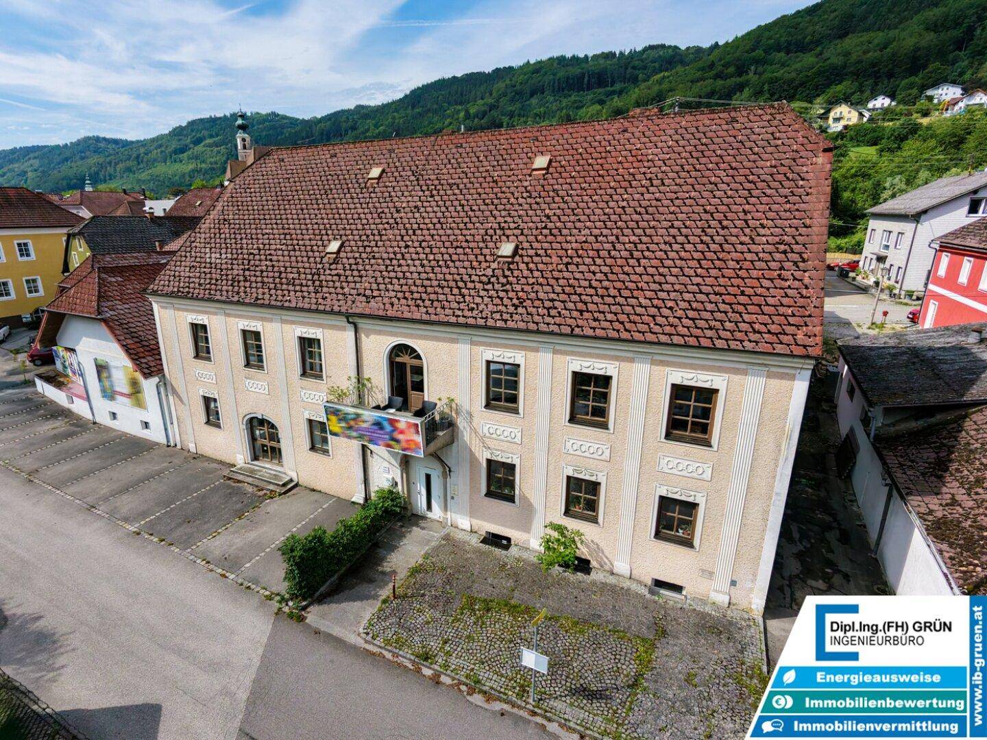 Vogelperspektive des historischen Gebäudes mit seiner charakteristischen Fassade und dem roten Ziegeldach.