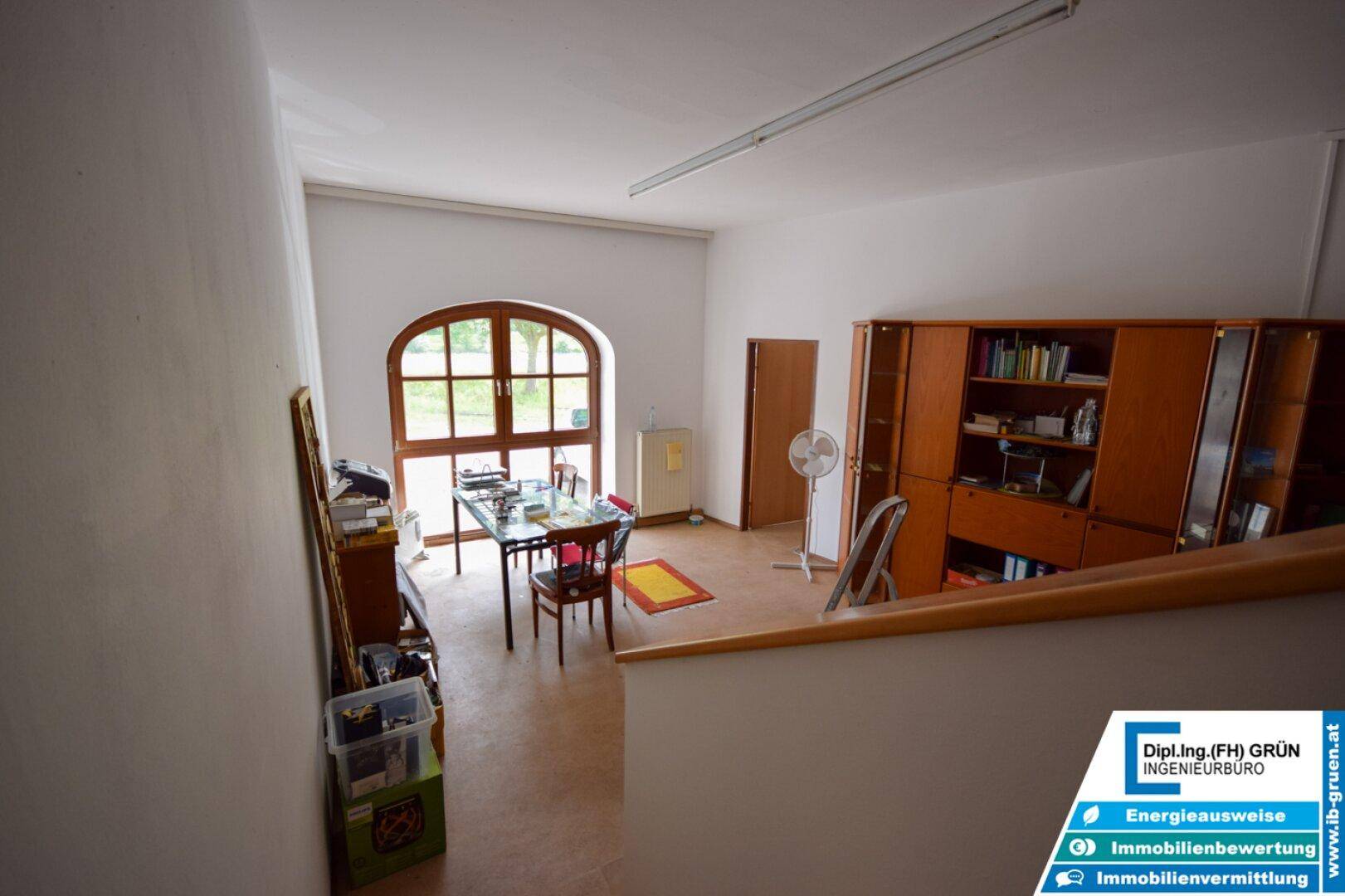 Geräumiger Raum mit großem Rundbogenfenster, Schreibtisch und Bücherregalen.