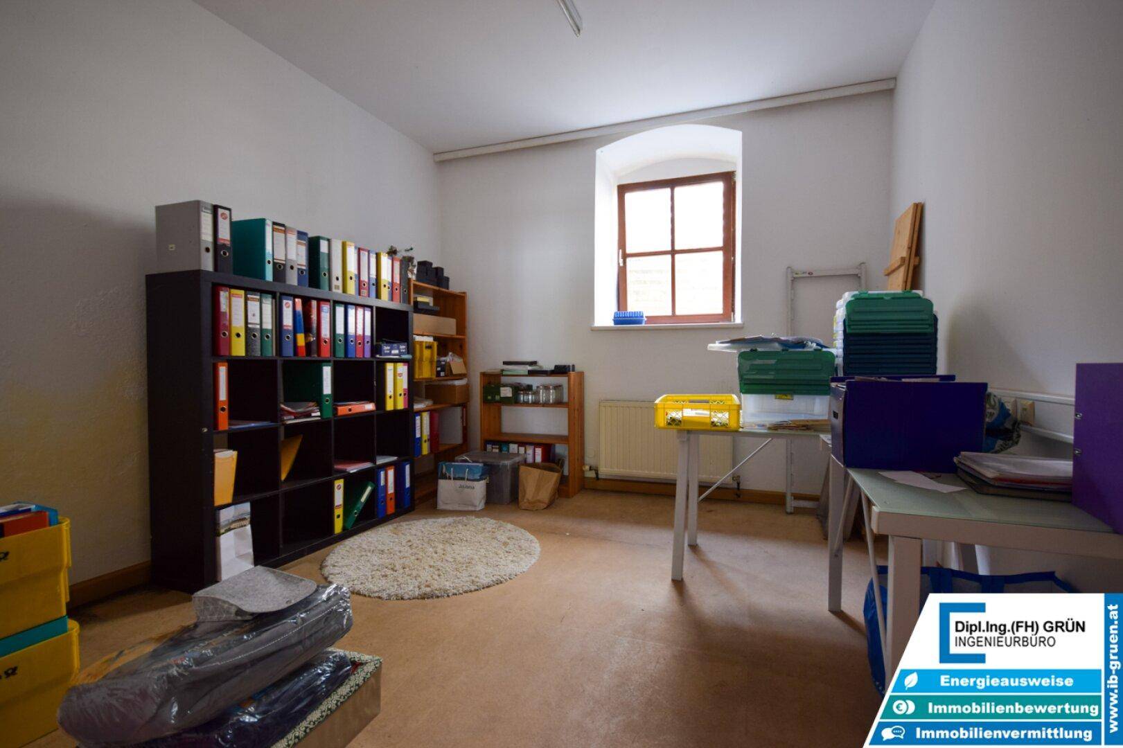 Funktionales Büro mit Regalen voller Aktenordner und einem kleinen Fenster.