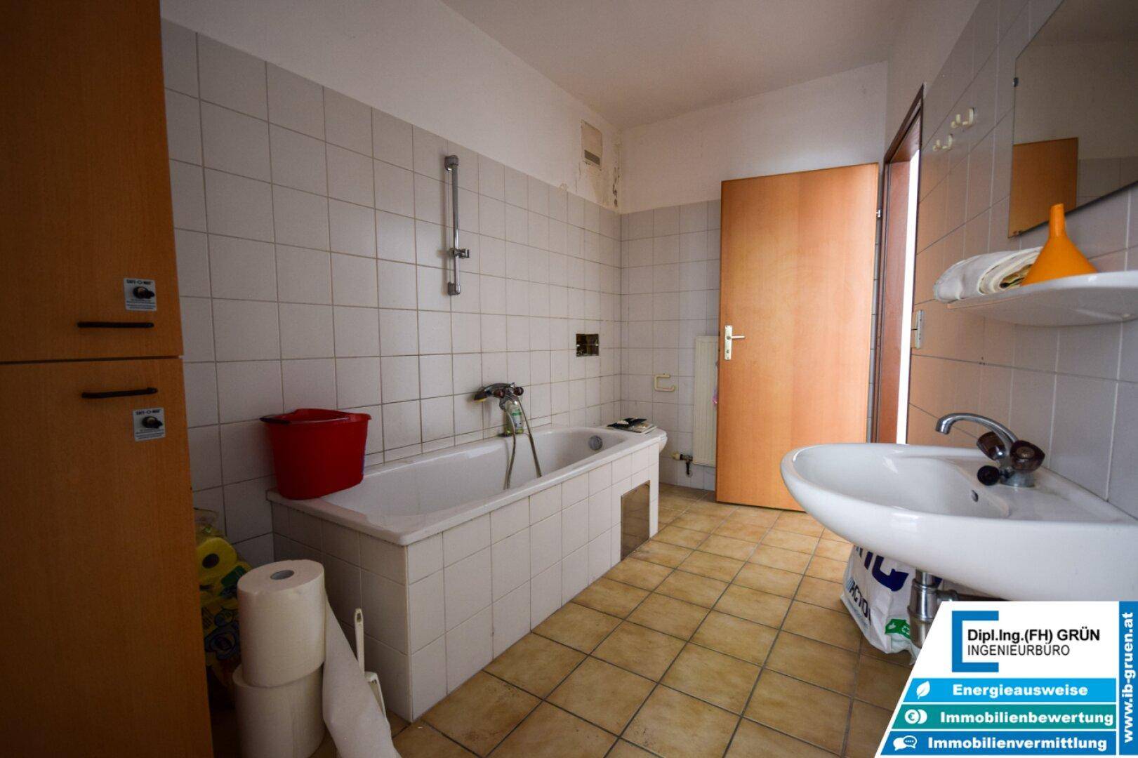 Badezimmer mit Badewanne, Waschbecken und weißen Wandfliesen, im Stil der 80er Jahre.