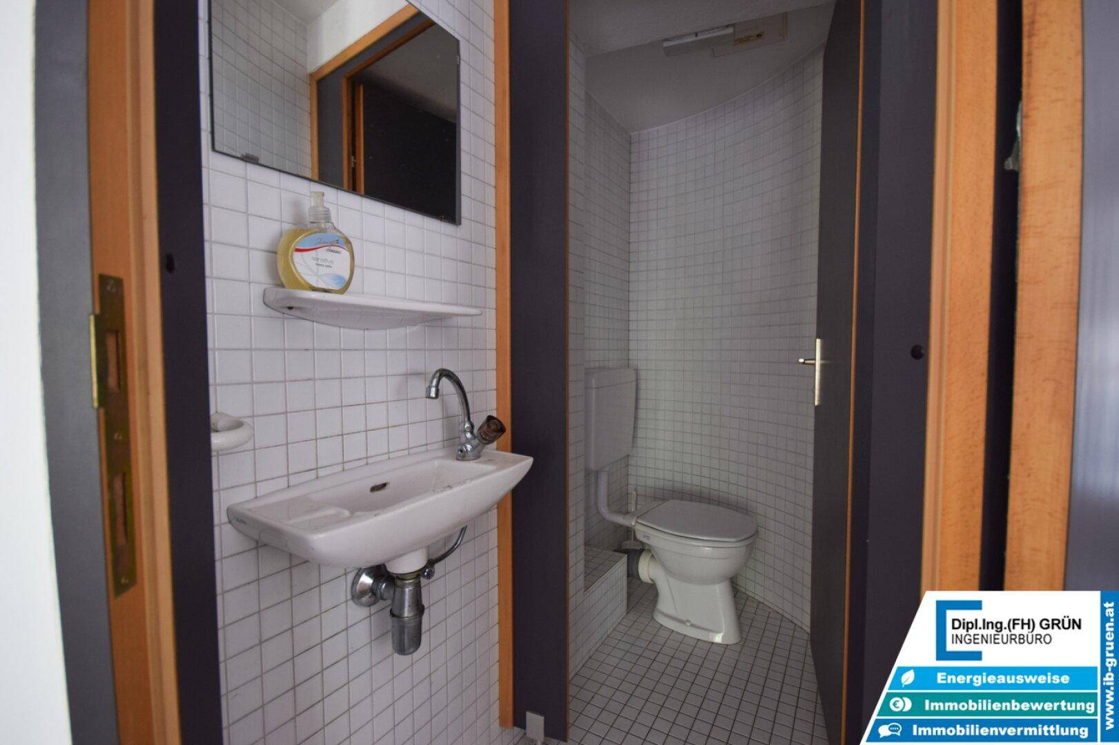 Kleines Gäste-WC mit Waschbecken, Toilette und weißen Fliesen an den Wänden.