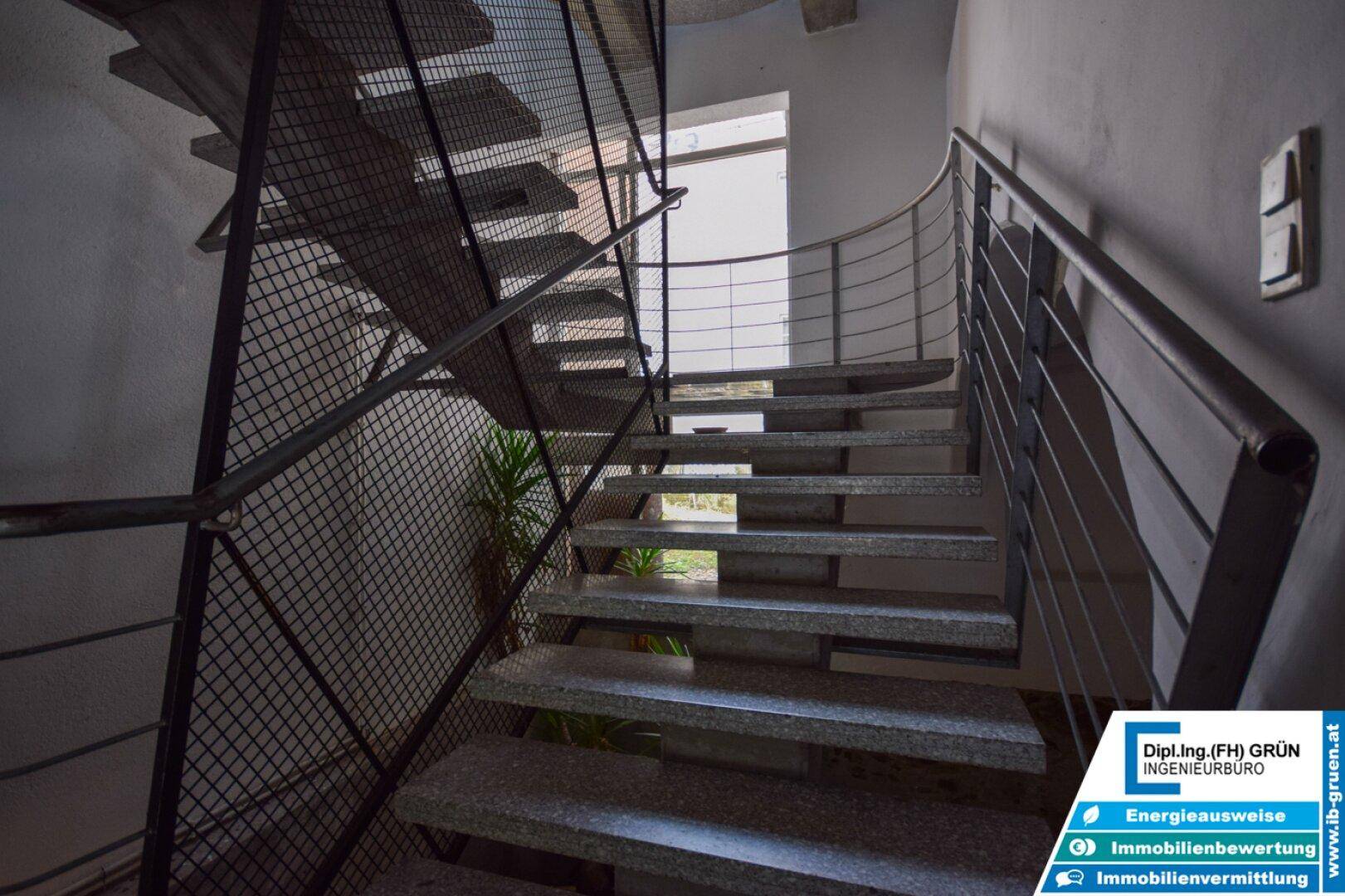 Industriell anmutendes Treppenhaus mit Metallgeländer und Steinstufen.