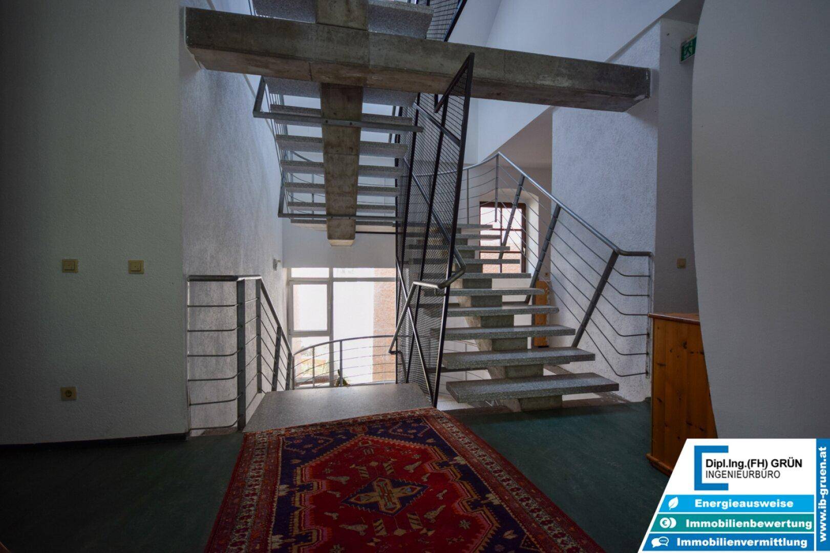 Mehrstöckiges Treppenhaus mit Metallgeländern und sichtbaren Betonbalken.
