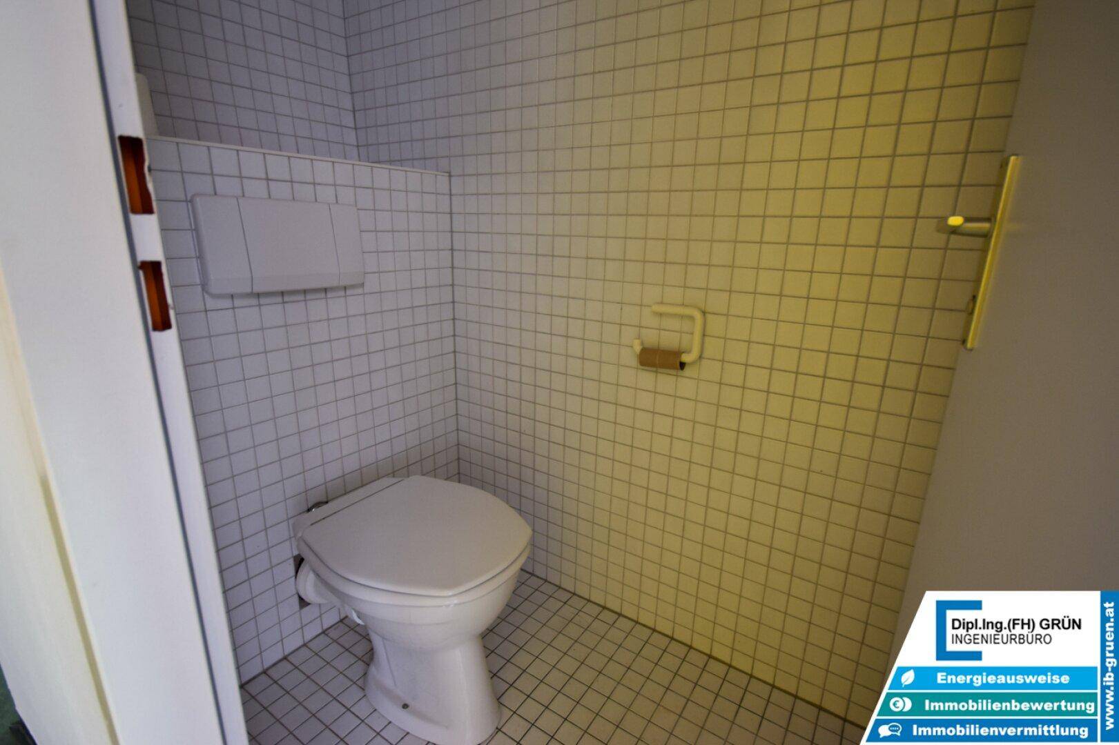Kleines WC mit weißen Fliesen und einfacher Toilette.