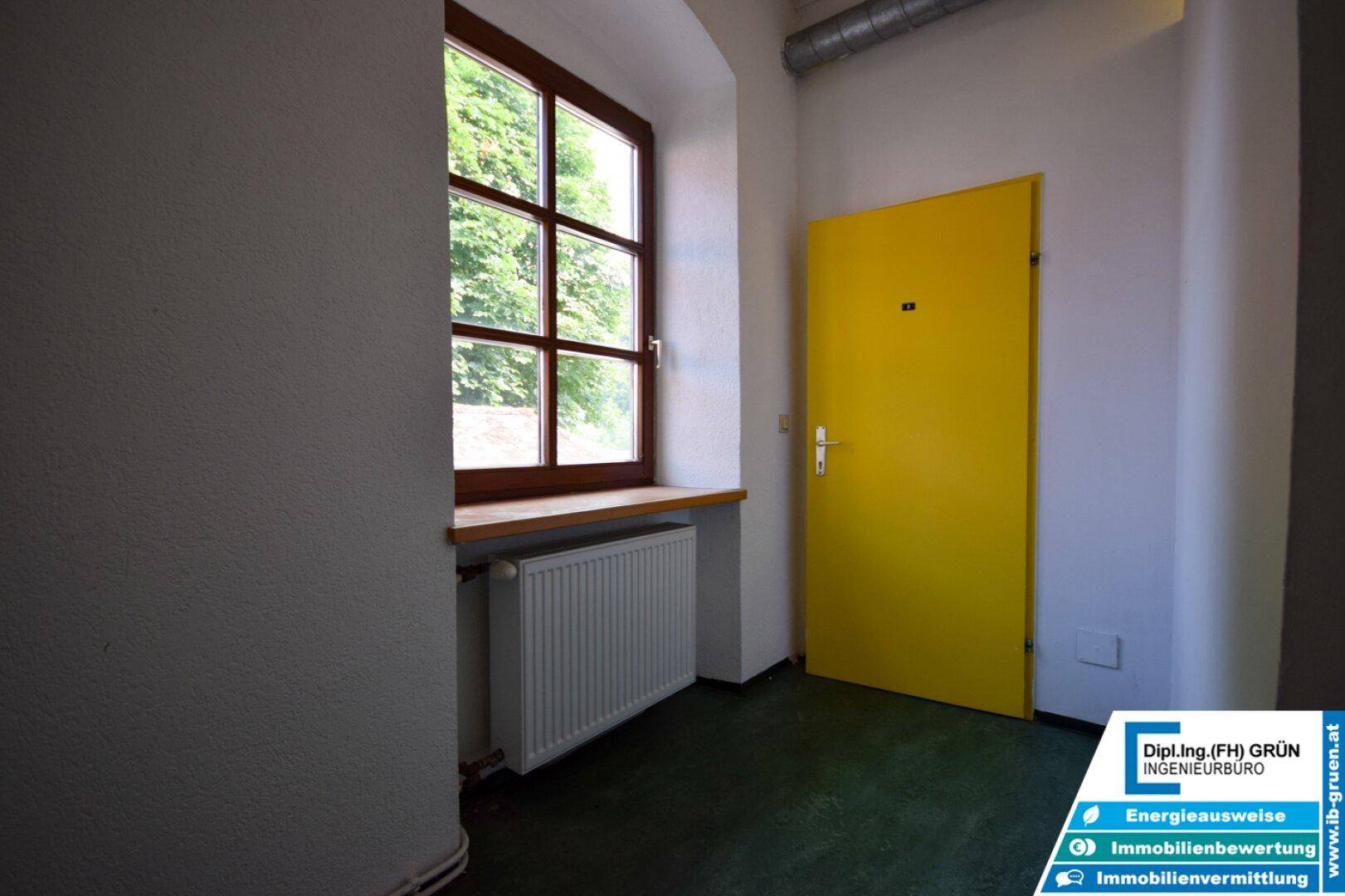 Flur mit gelber Tür, Fenster und Heizkörper.