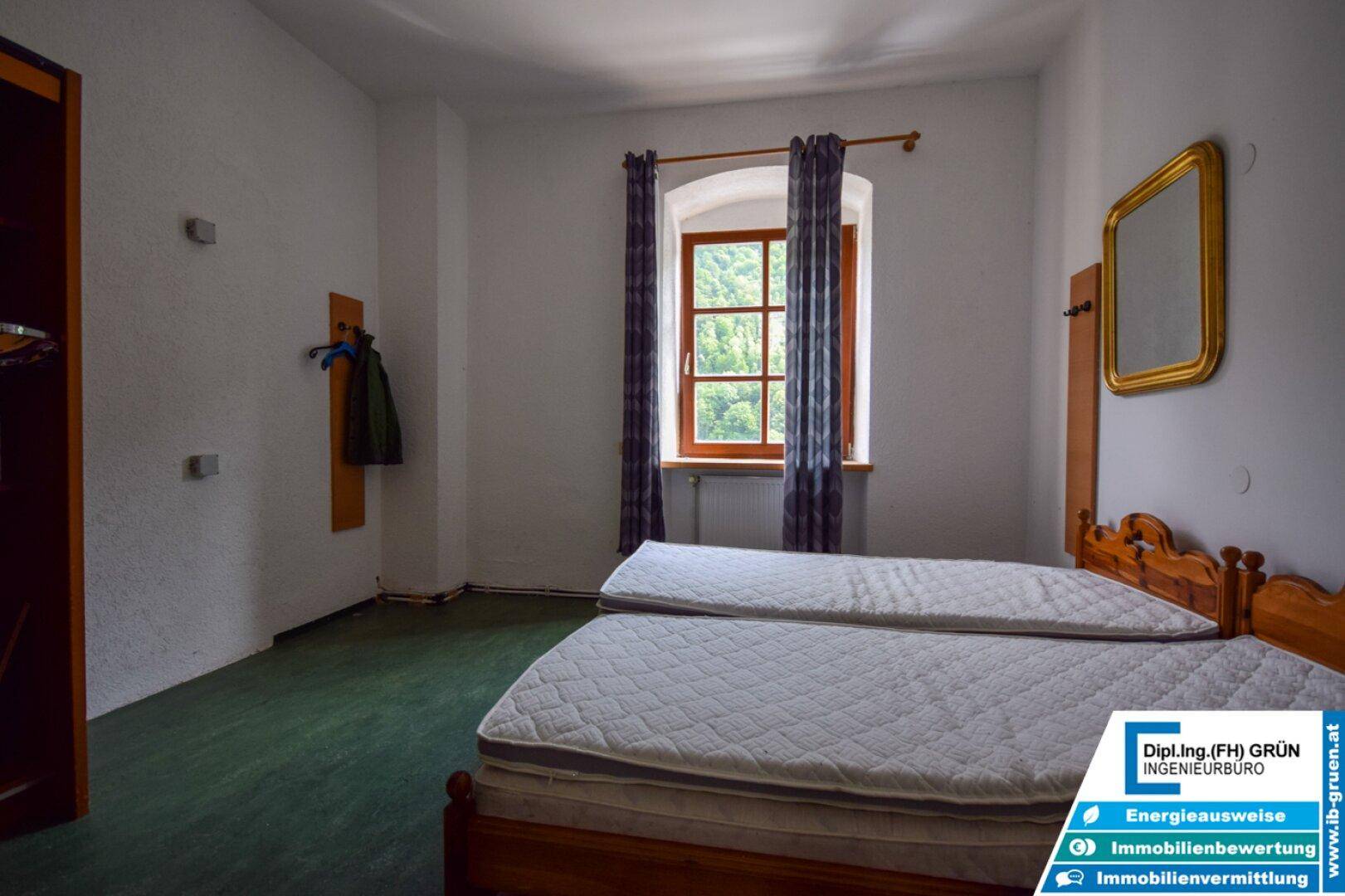 Schlafzimmer mit zwei Einzelbetten, Vorhängen und einem Fenster mit Grünblick.
