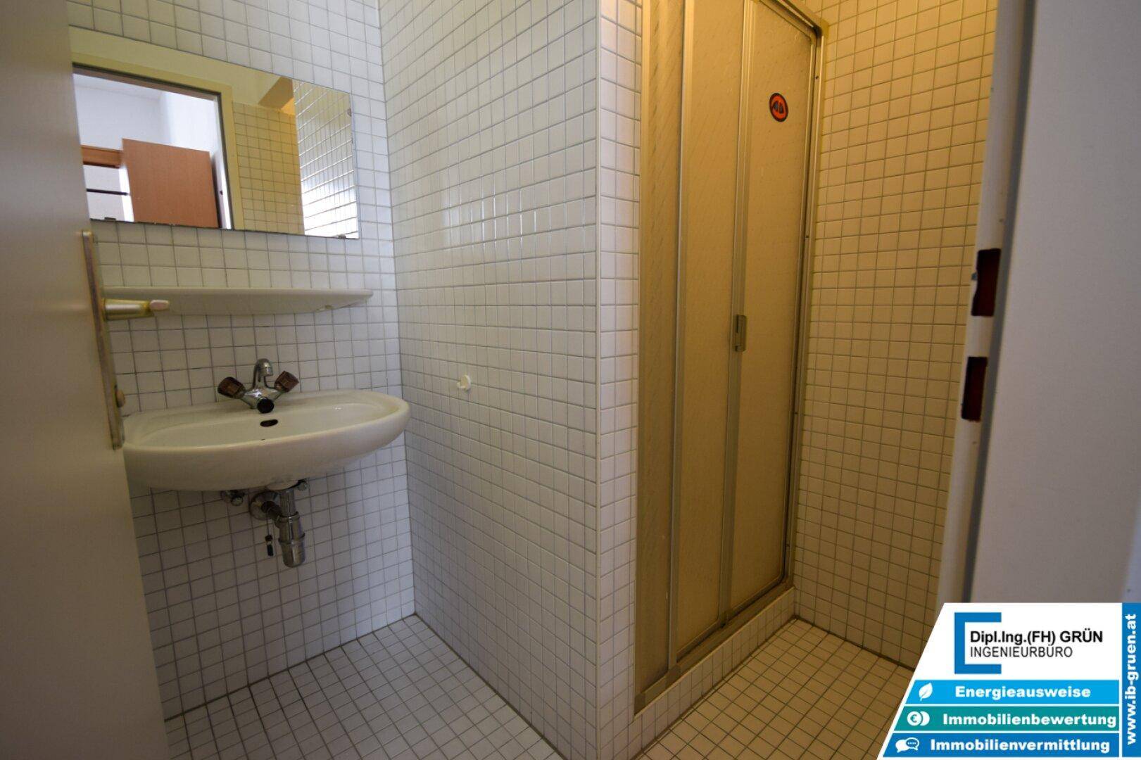 Badezimmer mit Duschkabine, Waschbecken und kleinen weißen Fliesen.