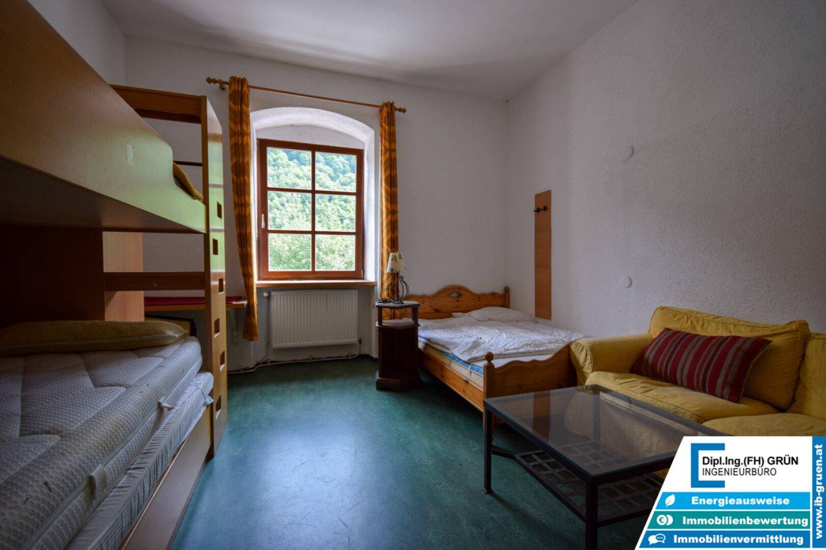 Geräumiges Schlafzimmer mit Etagenbett, Einzelbett und gelbem Sofa.