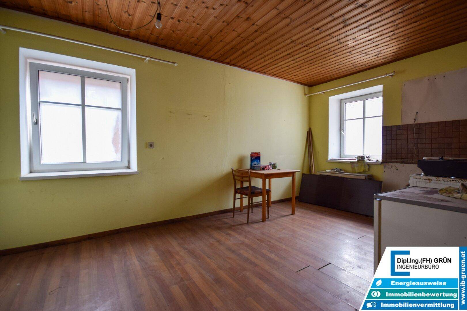 Geräumiger Raum mit Holzdecke, gelben Wänden und einem kleinen Tisch.