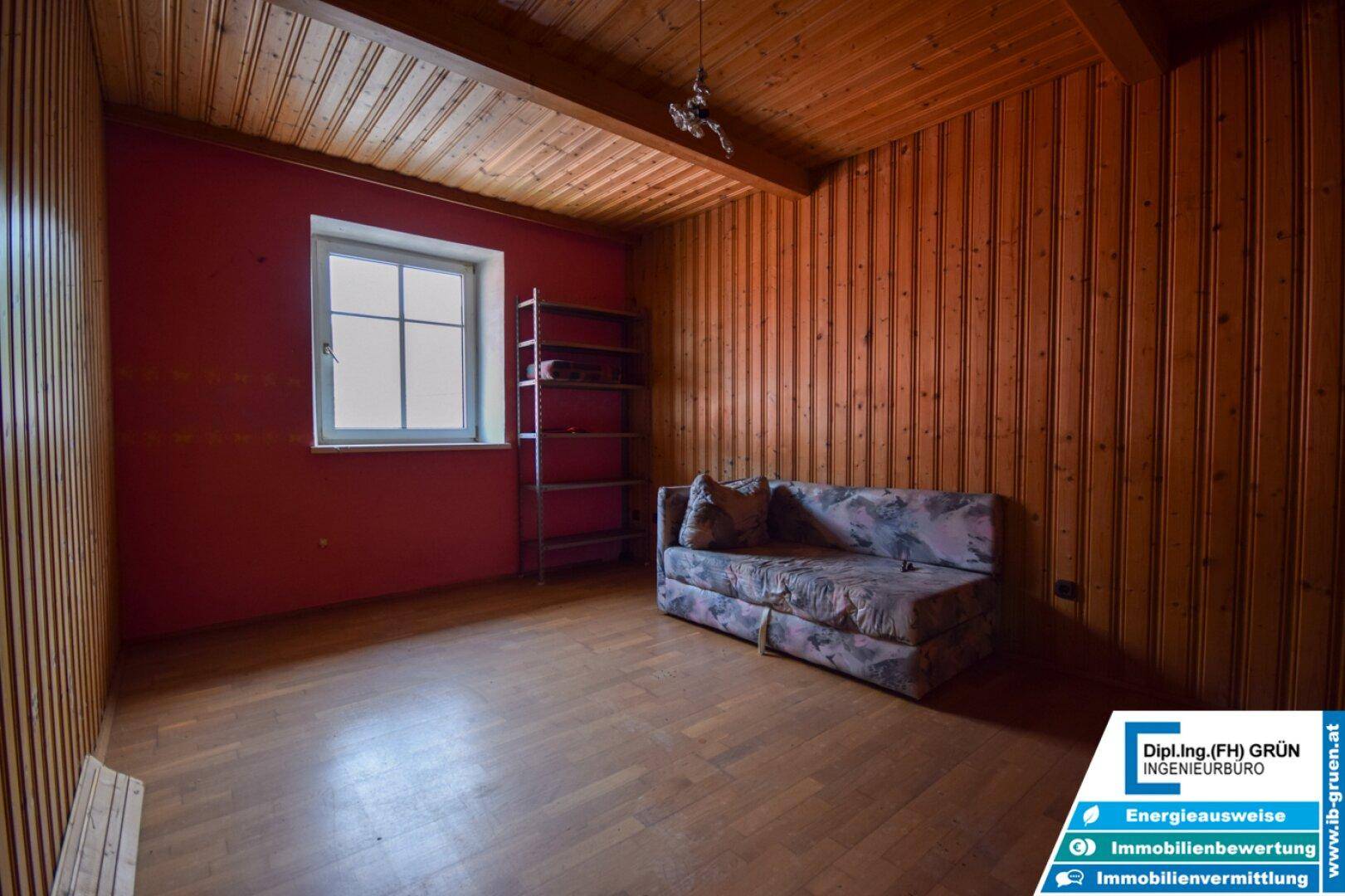 Schlafzimmer mit Holzwänden, Holzdecke, Holzboden und einem Sofa.