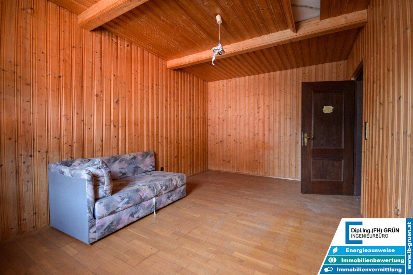 Gemütliches Schlafzimmer mit Holzwänden, Holzdecke und einem Sofa.