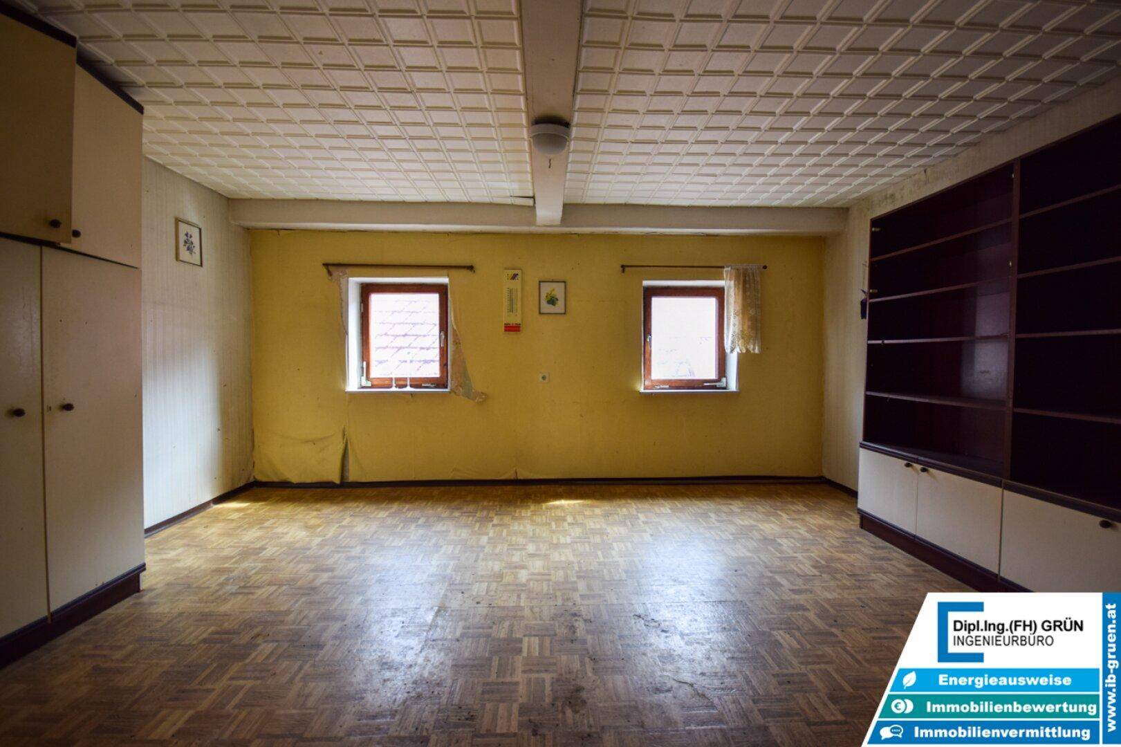Großer Raum mit gelben Wänden, Holzboden und einer strukturierten Decke.