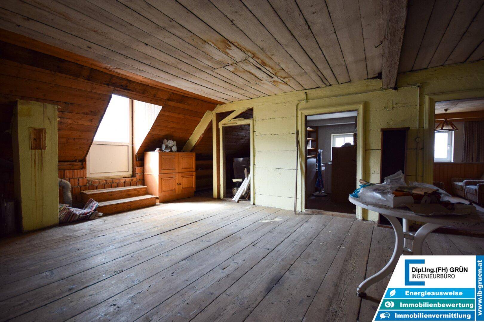 Geräumiger Dachboden mit sichtbaren Holzbalken, Dielenboden und schrägen Wänden, ideal als Stauraum.