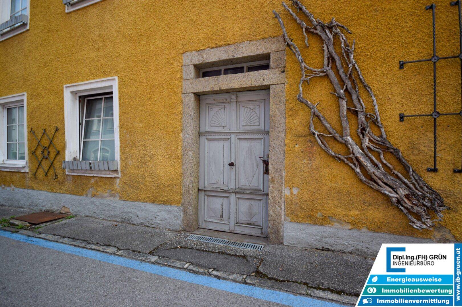 Detailansicht des historischen Hauseingangs mit Holztür und gelber Fassade.