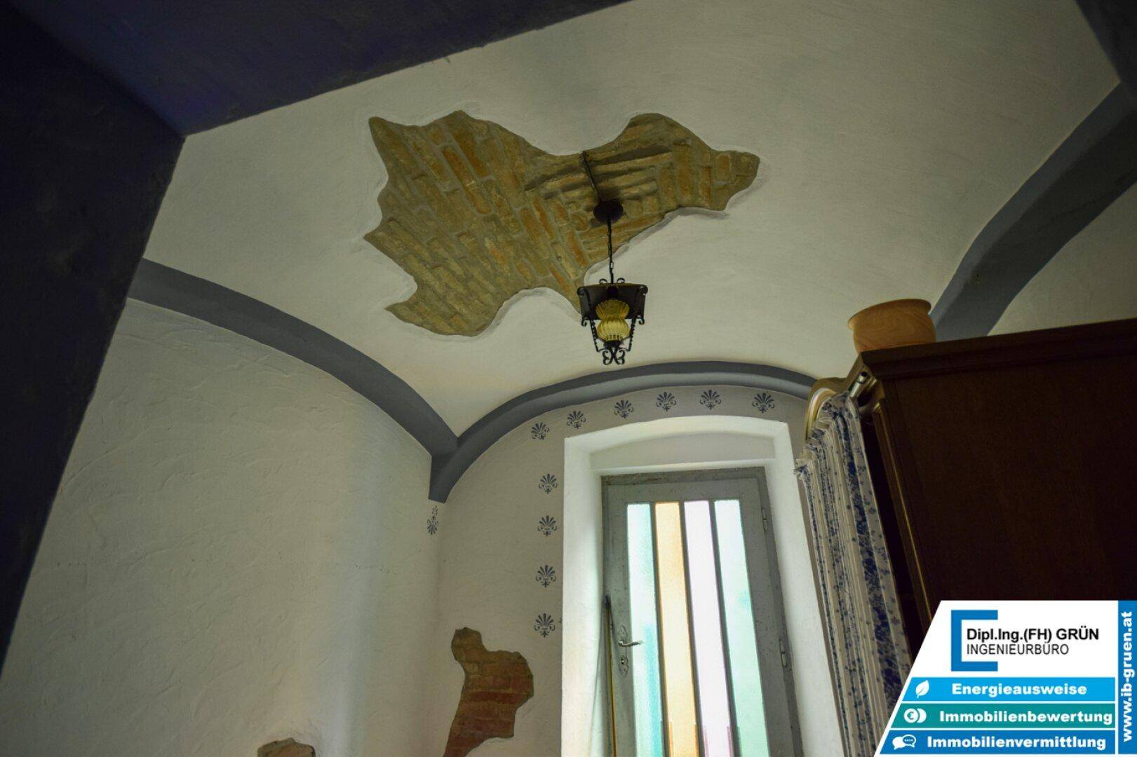 Detailansicht einer Gewölbedecke mit freigelegten Ziegeln und einer historischen Lampe.