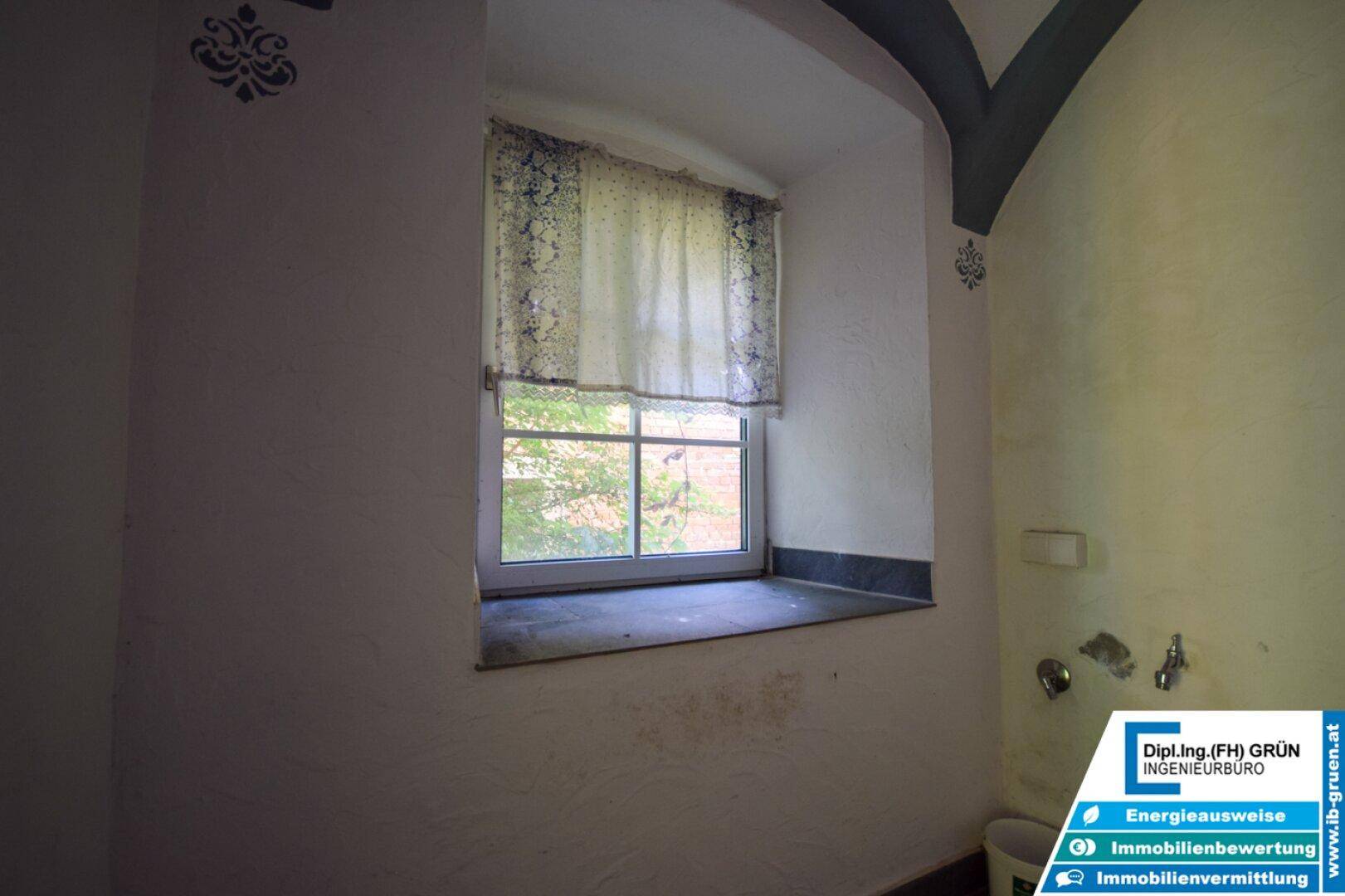 Kleiner Raum mit Fenster, einfacher Einrichtung und traditionellen Wandverzierungen.