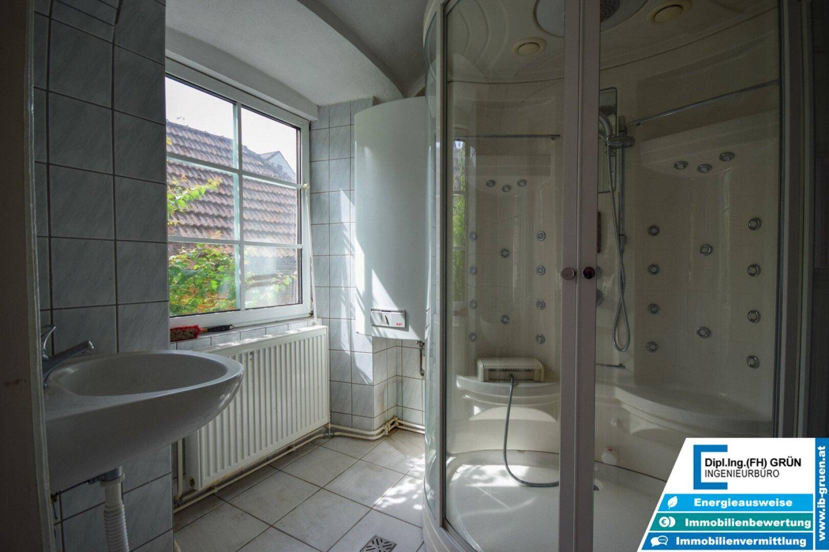 Helles Badezimmer mit Duschkabine, Waschbecken und Fenster.