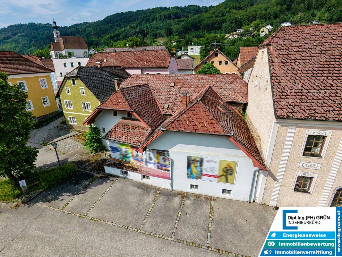 Überblick über ein Gebäudeensemble mit traditionellen Dächern und einer Kirche im Hintergrund.