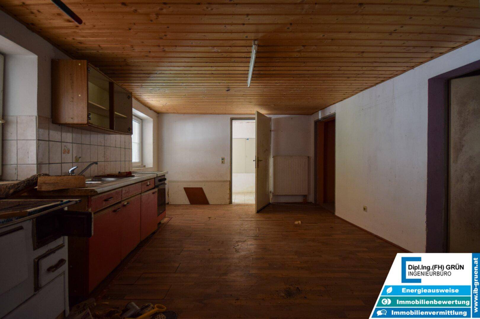 Rustikale Küche mit Holzboden, alten Einbauschränken und einem traditionellen Holzofen.